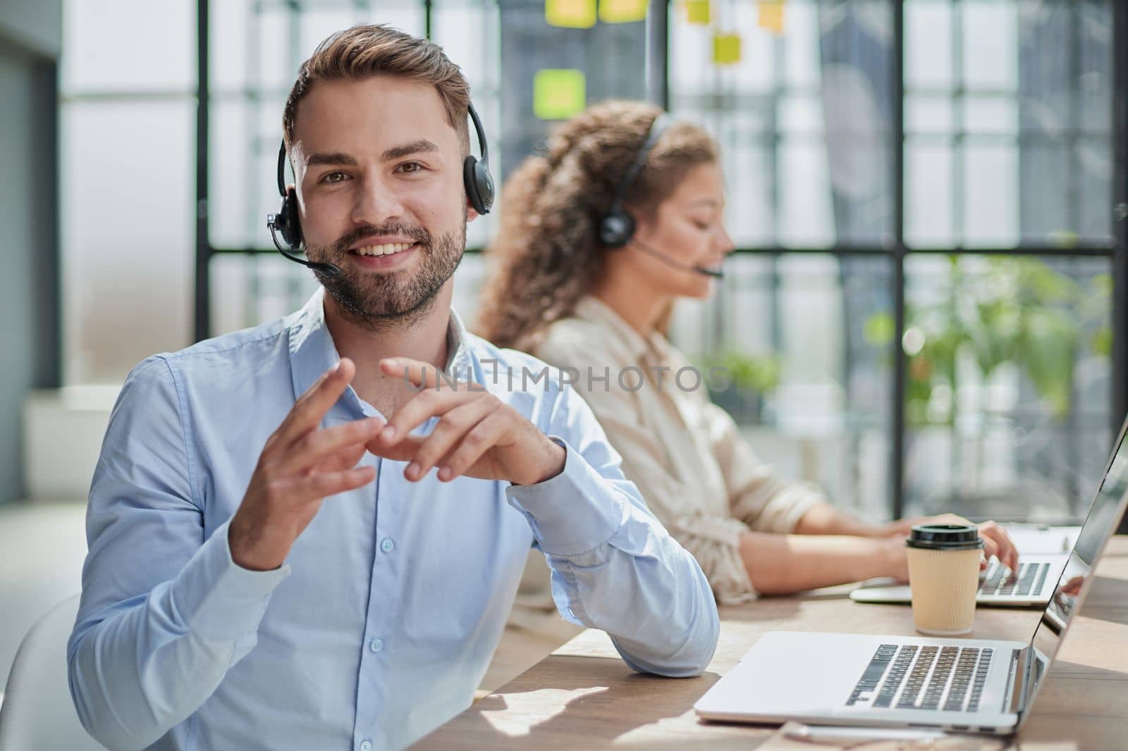 Handsome male customer service agent working in call center office as a telemarketer.