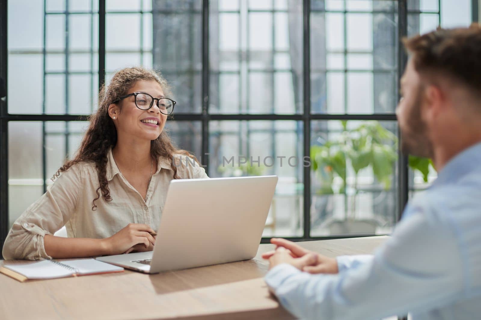 manager in glasses sitting at the table receives a client in the office by Prosto