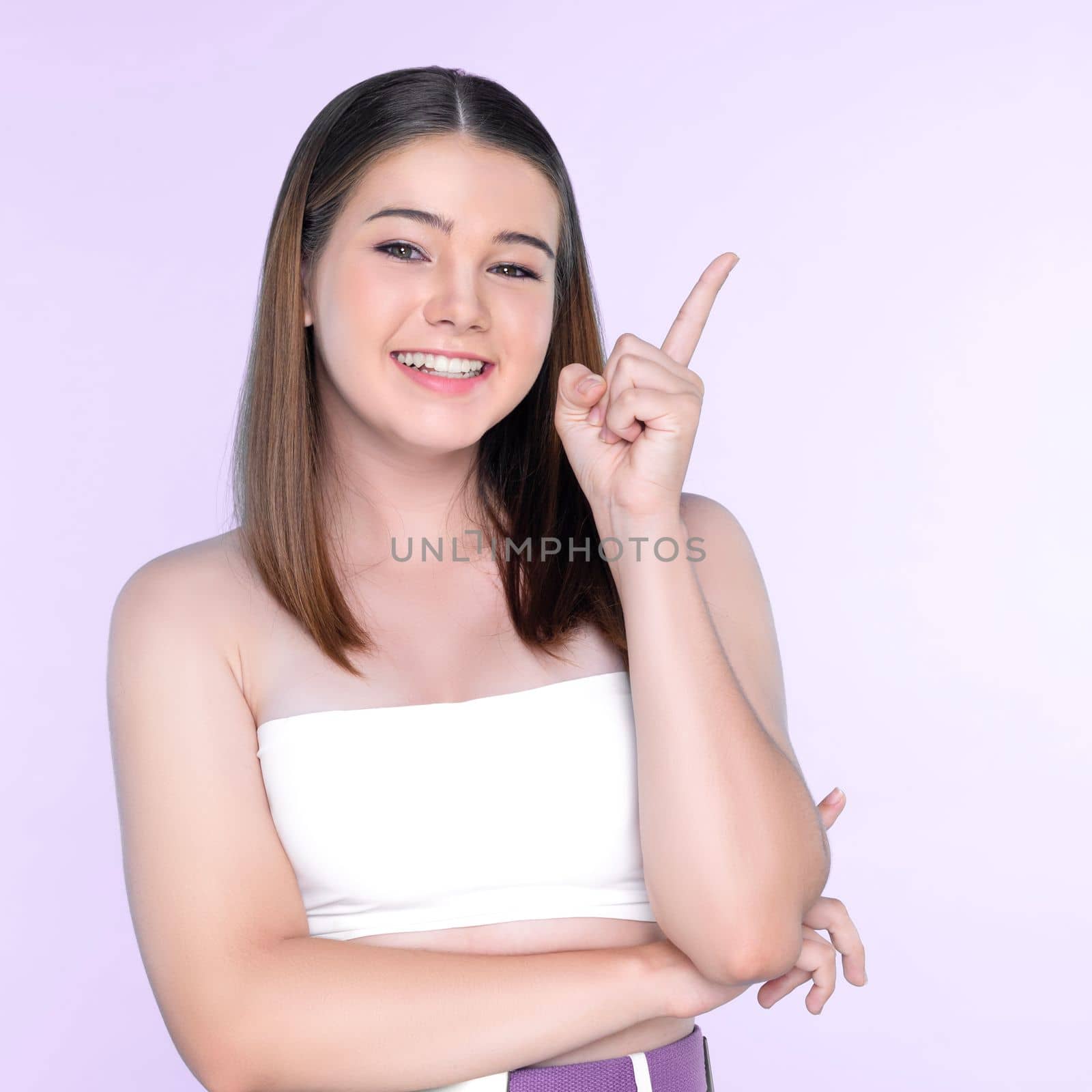 charming young girl with perfect fresh skin pointing finger. Beauty and skincare by biancoblue