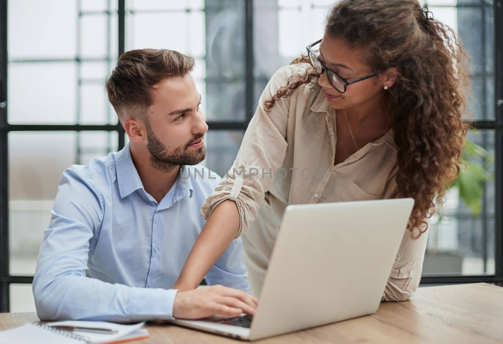 Colleagues check documents using a laptop. A man and a woman are sitting together looking at a laptop. business concept by Prosto