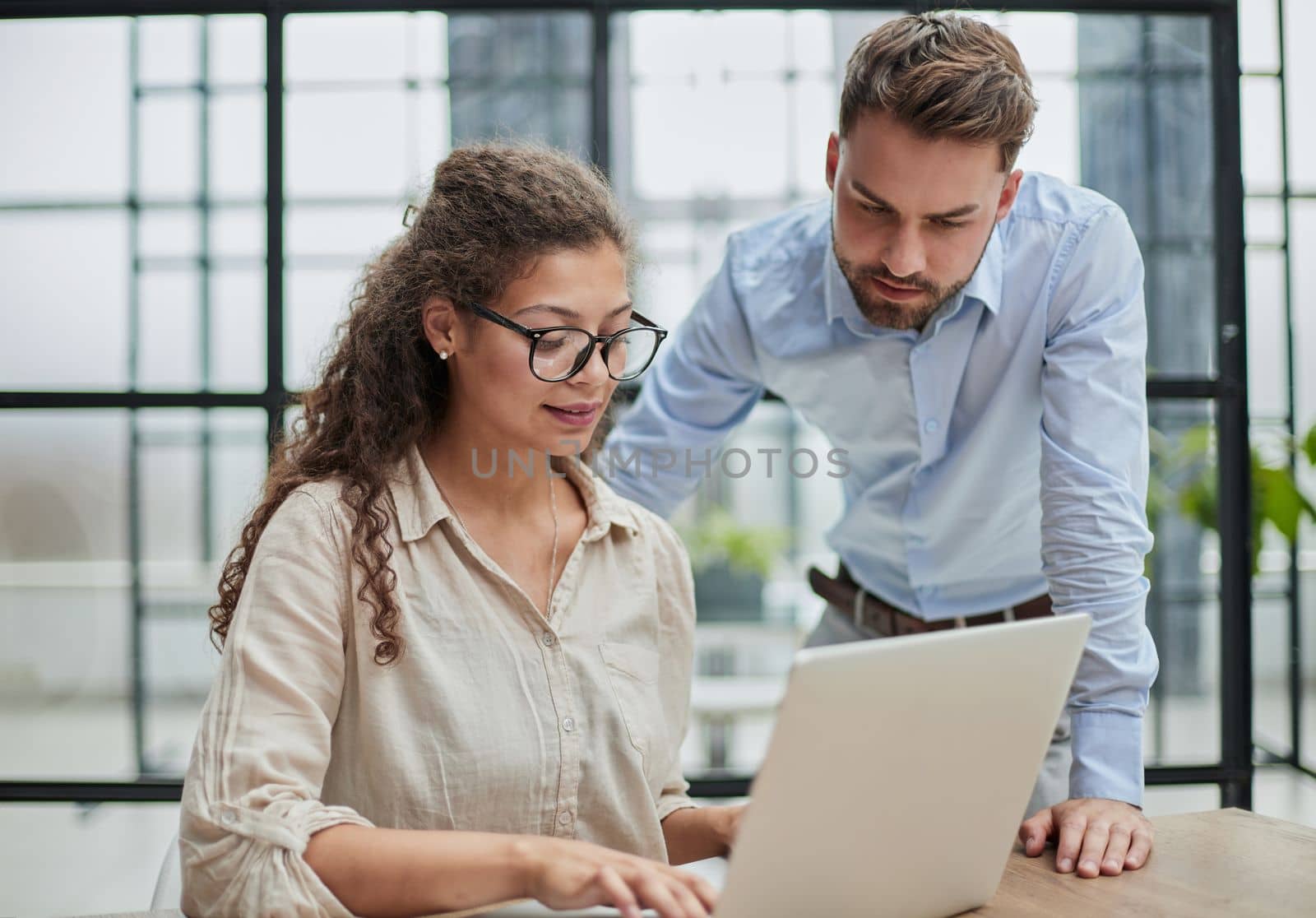 Colleagues check documents using a laptop. A man and a woman are sitting together looking at a laptop. business concept