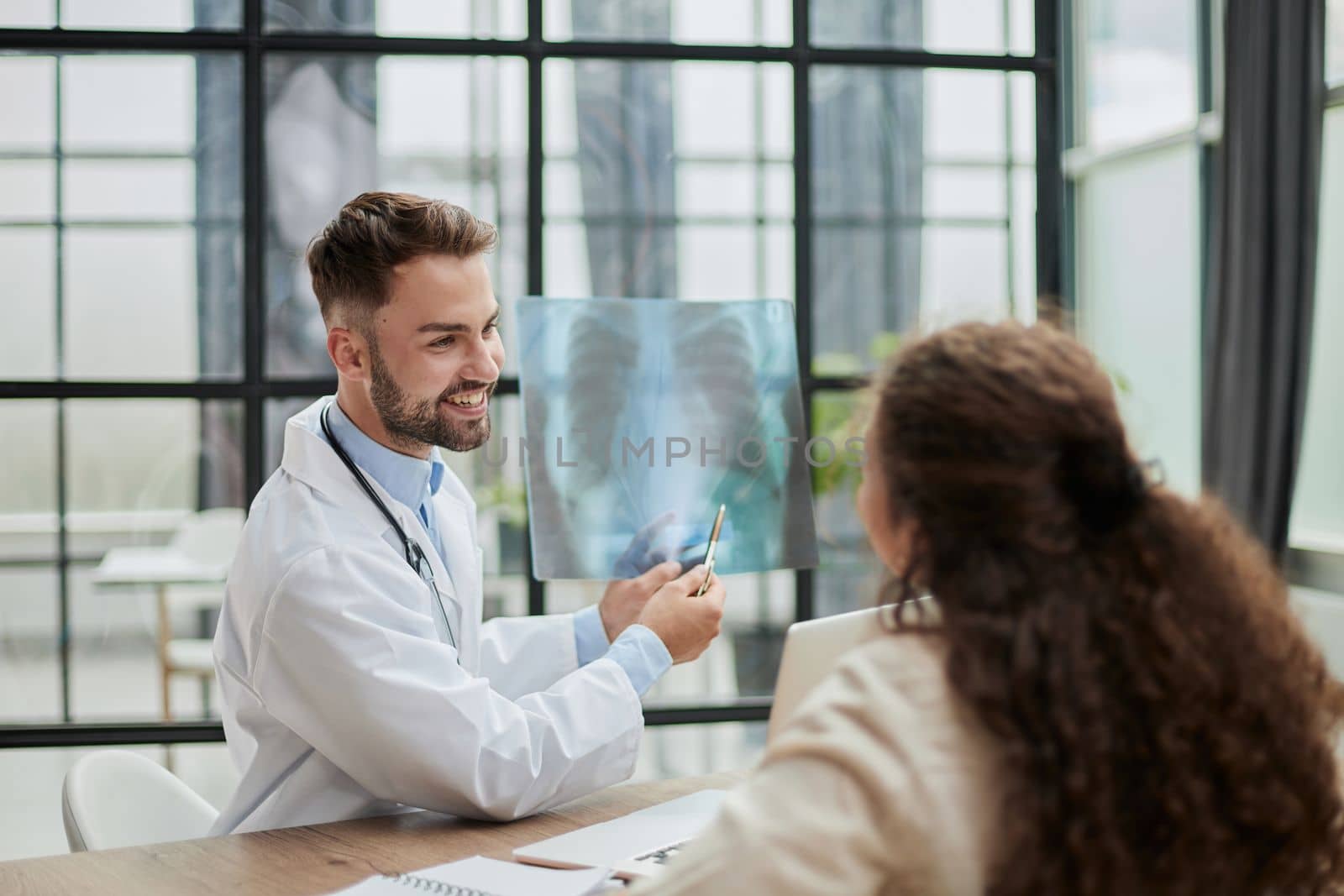 Concentrated male doctor looking at x-ray picture of spine by Prosto