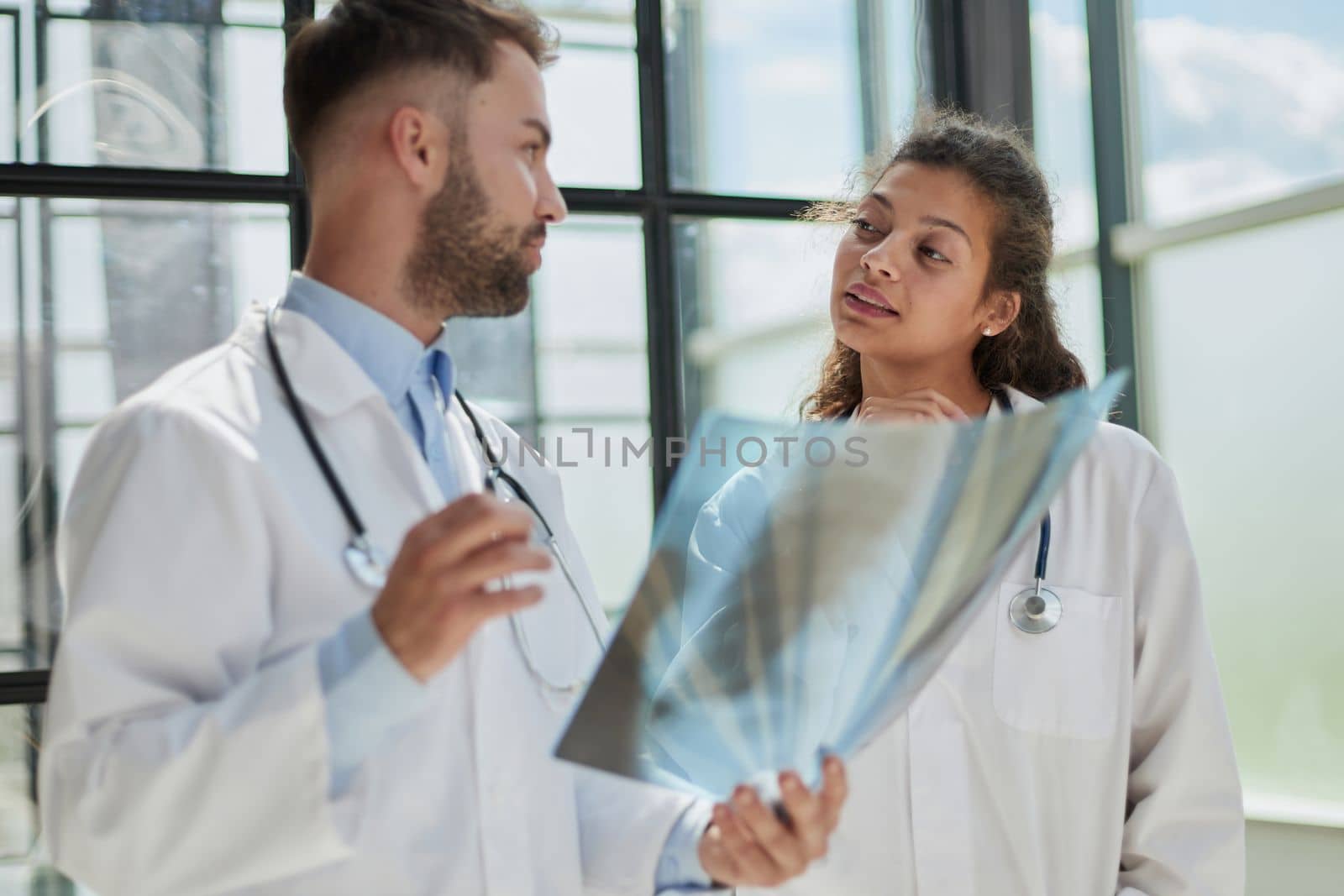 Young serious competent male doctor looking at X-ray at doctor's office by Prosto