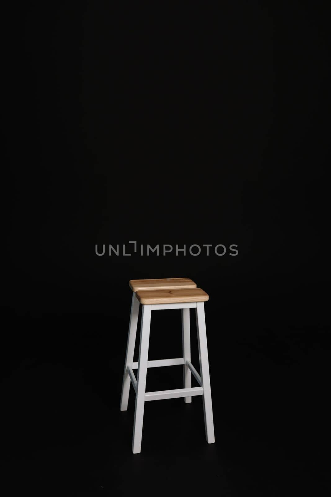 minimalistic wooden chair against black background. Concept modern interior and design furniture in room. High stool in loft style. Retro Bar chair. Vintage wooden metal chair