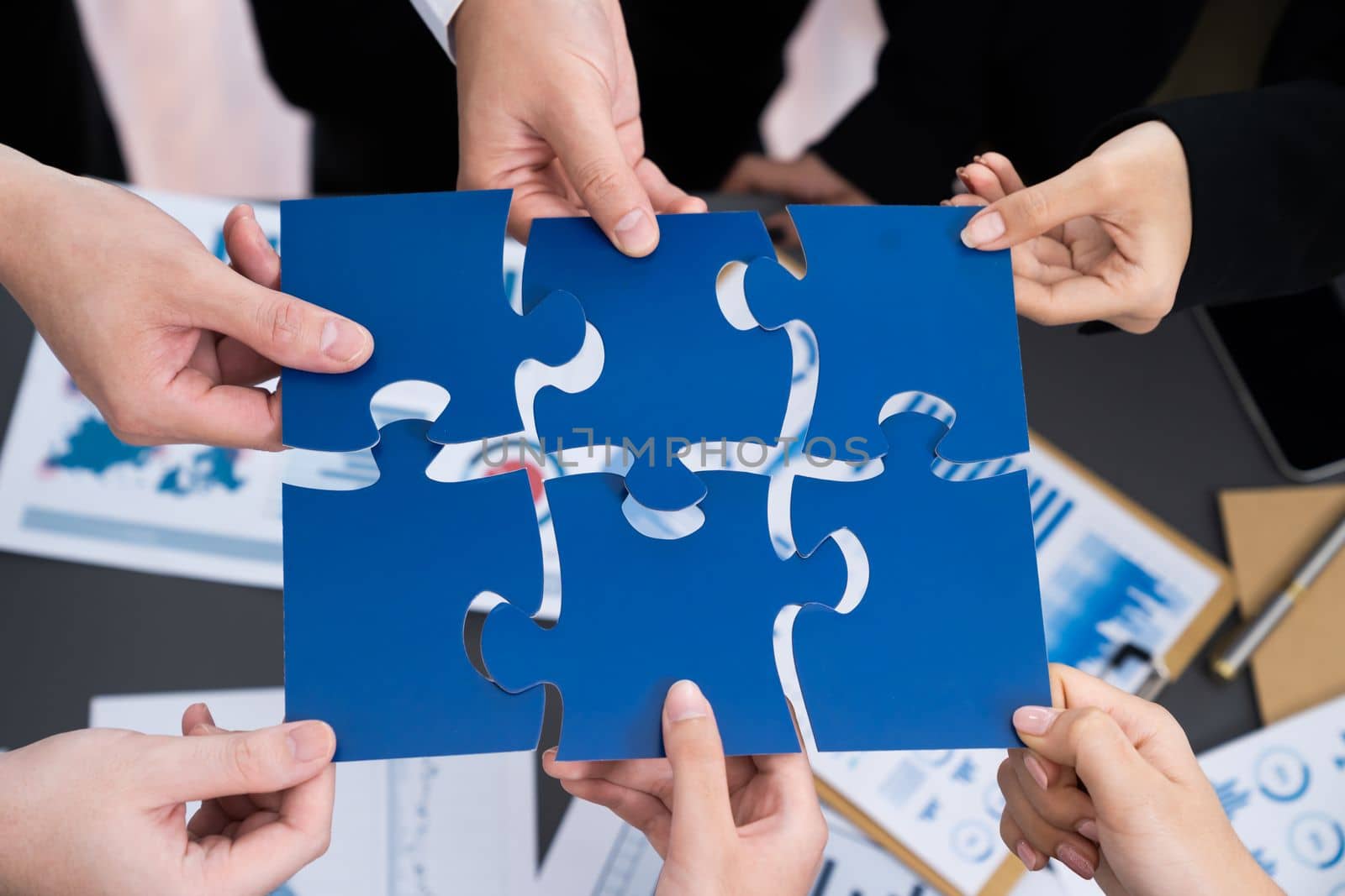 Closeup top view business people join jigsaw puzzle together in harmony office by biancoblue