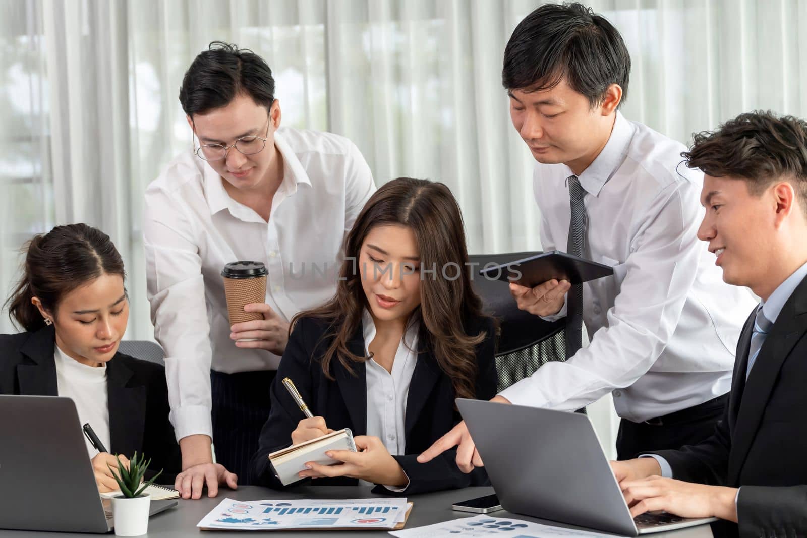 Harmony in office concept as business people analyzing dashboard paper together in workplace. Young colleagues give ideas at manager desk for discussion or strategy planning about project.