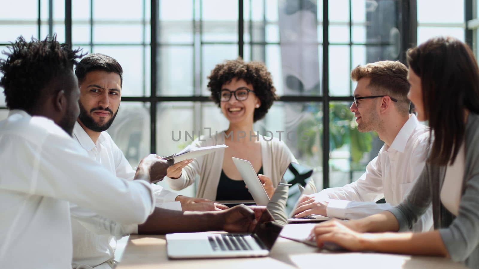 Happy young female employee discussing online project, showing computer presentation to skilled team leader in eyeglasses. Friendly diverse colleagues working in pairs on laptop, using applications.