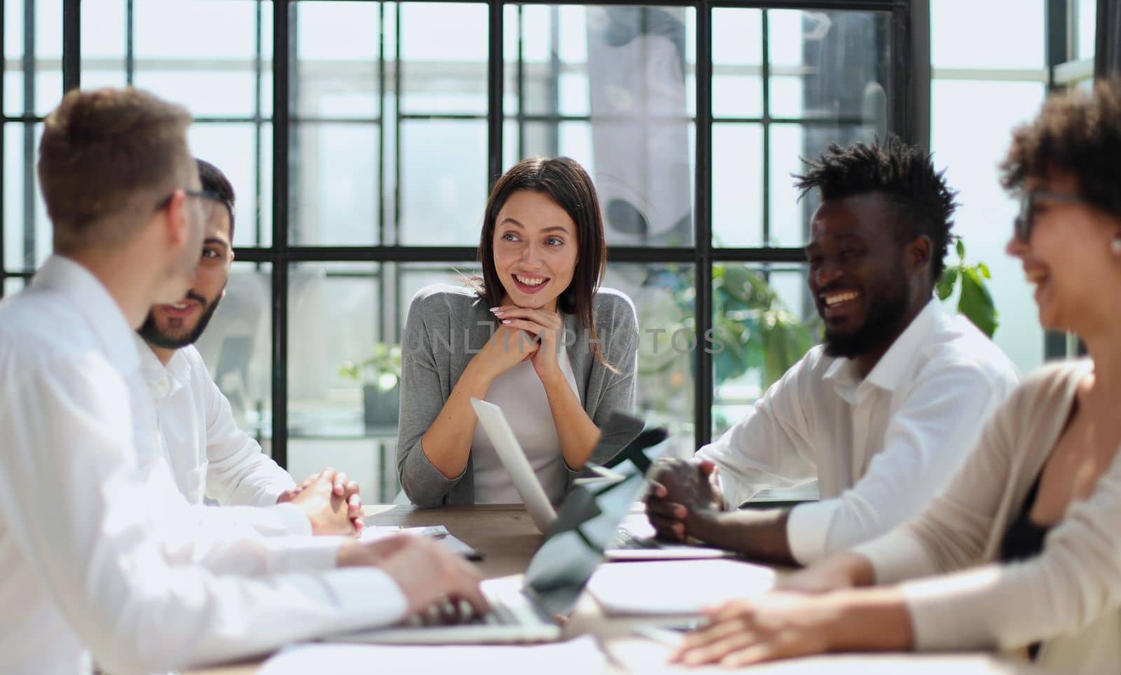 Happy young female employee discussing online project, showing computer presentation to skilled team leader in eyeglasses. Friendly diverse colleagues working in pairs on laptop, using applications.