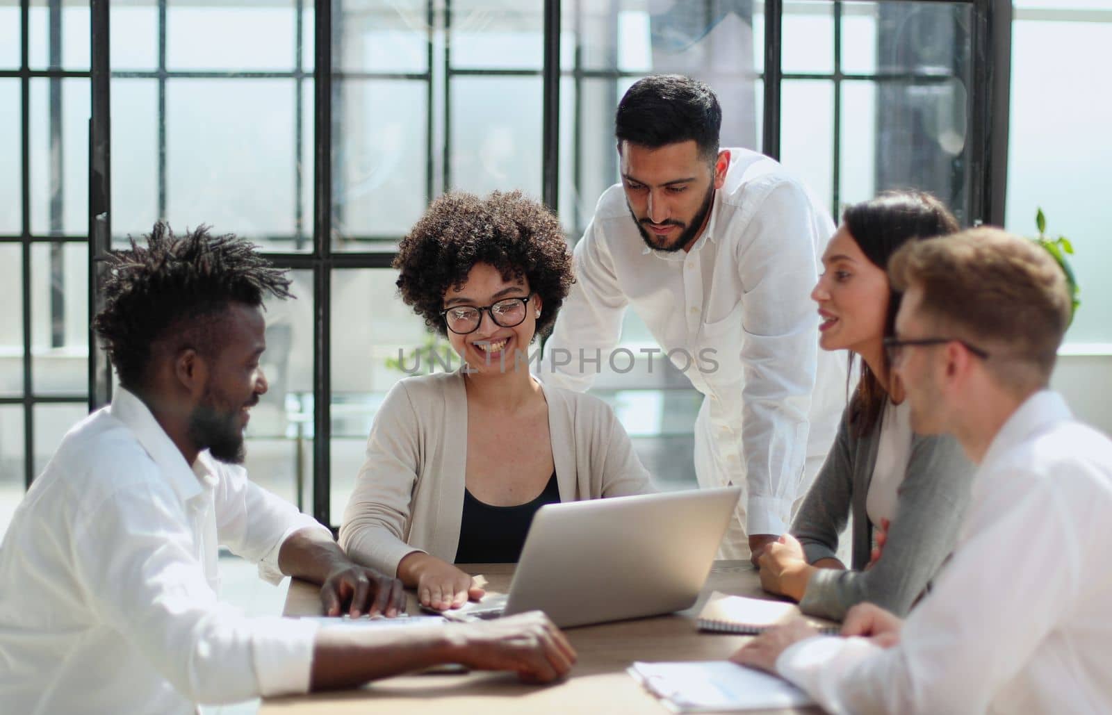 Happy young female employee discussing online project, showing computer presentation to skilled team leader in eyeglasses. Friendly diverse colleagues working in pairs on laptop, using applications.