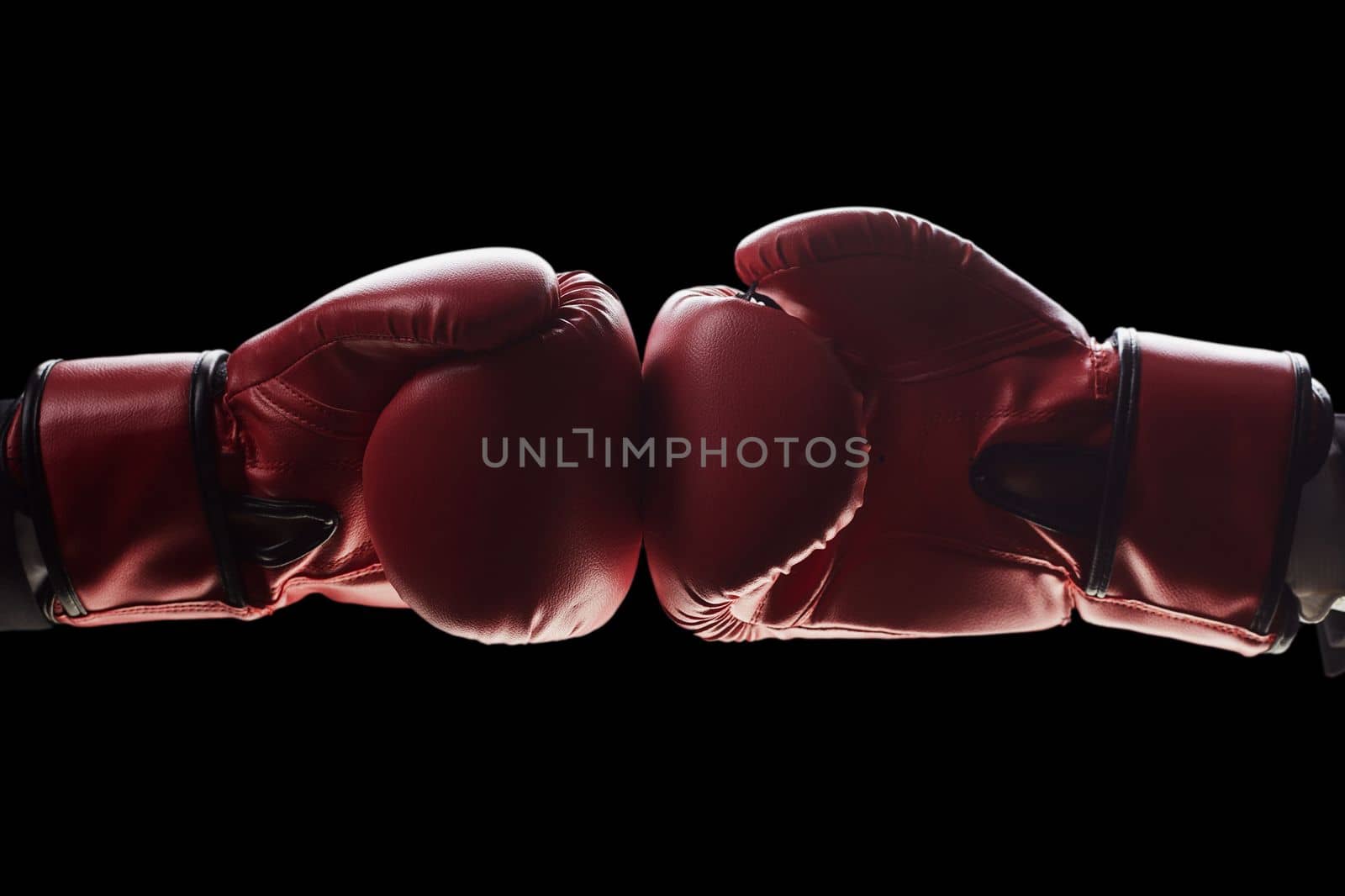 Two men's hands in boxing gloves. The concept of confrontation. Photo on a black background