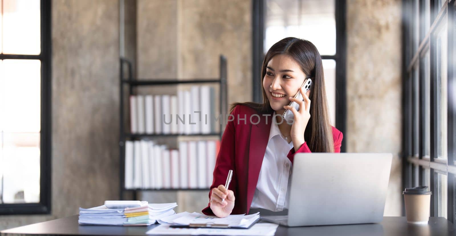 Portrait of a cheerful young business Asian woman using smartphone application in workplace office, concept of Small business employee freelance online sme marketing e-commerce telemarketing...