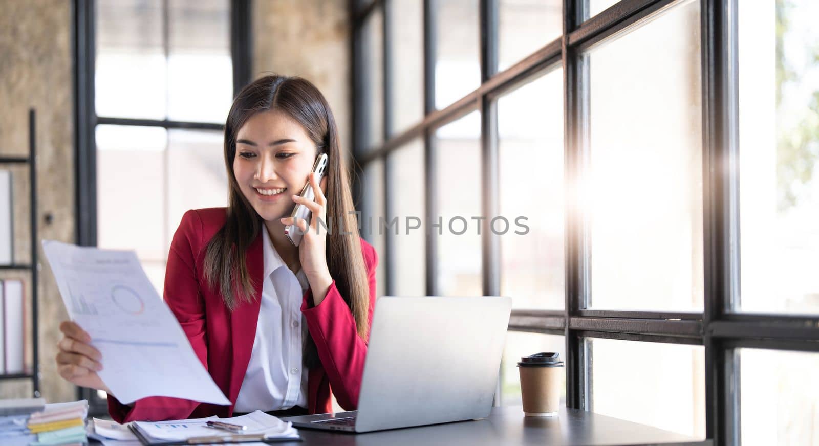 Portrait of a cheerful young business Asian woman using smartphone application in workplace office, concept of Small business employee freelance online sme marketing e-commerce telemarketing...