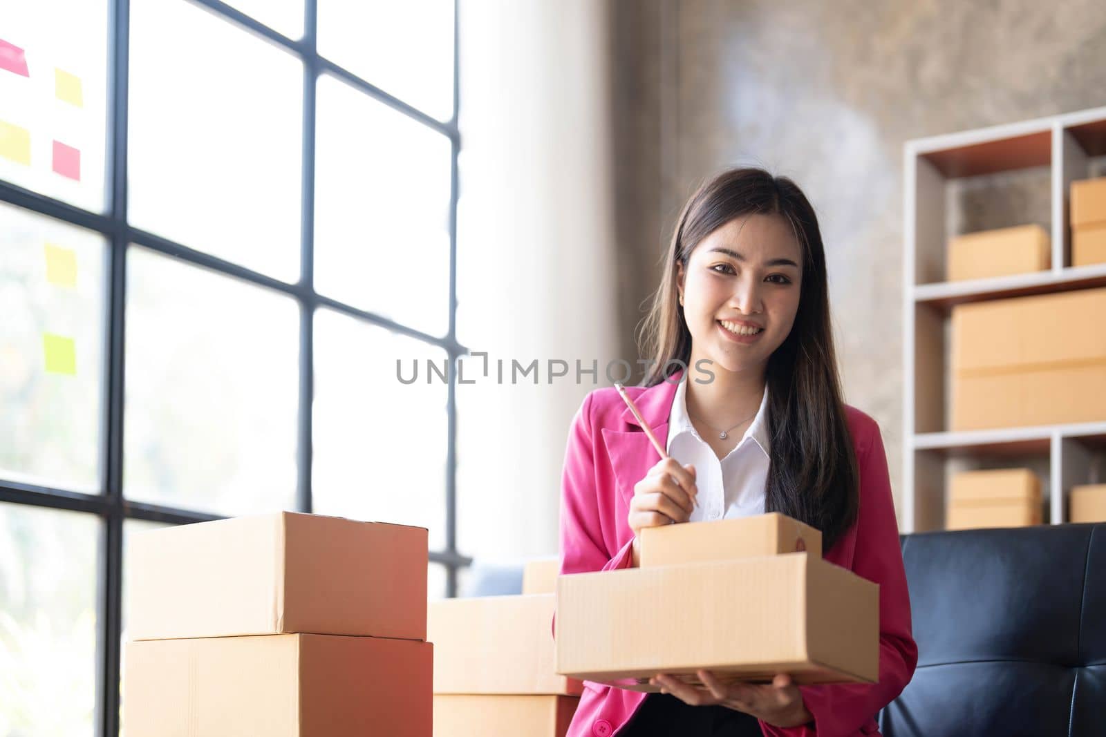 Startup small business SME, Entrepreneur owner using smartphone or tablet taking receive and checking online purchase shopping order to preparing pack product box. Selling online ideas concept..