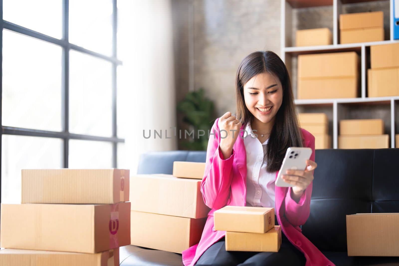 Startup SME small business entrepreneur of freelance Asian woman using a laptop with box Cheerful success happy Asian woman her hand lifts up online marketing packaging and delivery SME idea concept by wichayada