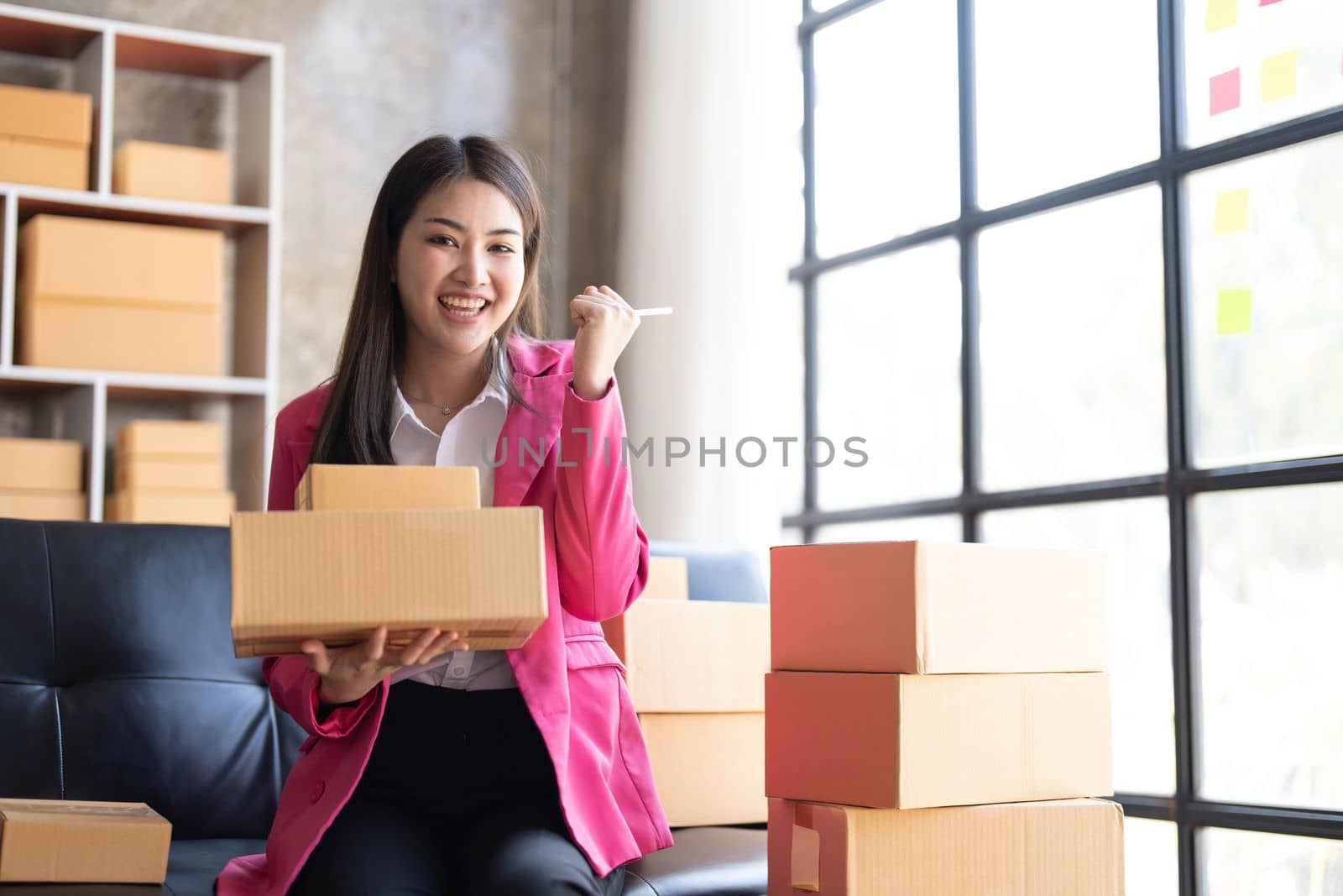 Startup SME small business entrepreneur of freelance Asian woman using a laptop with box Cheerful success happy Asian woman her hand lifts up online