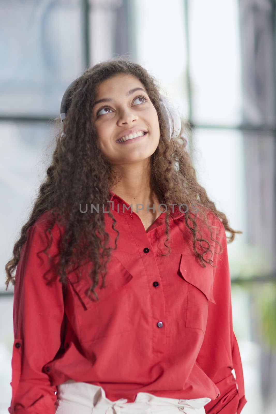 Beautiful smiling young woman in headphones in modern office by Prosto