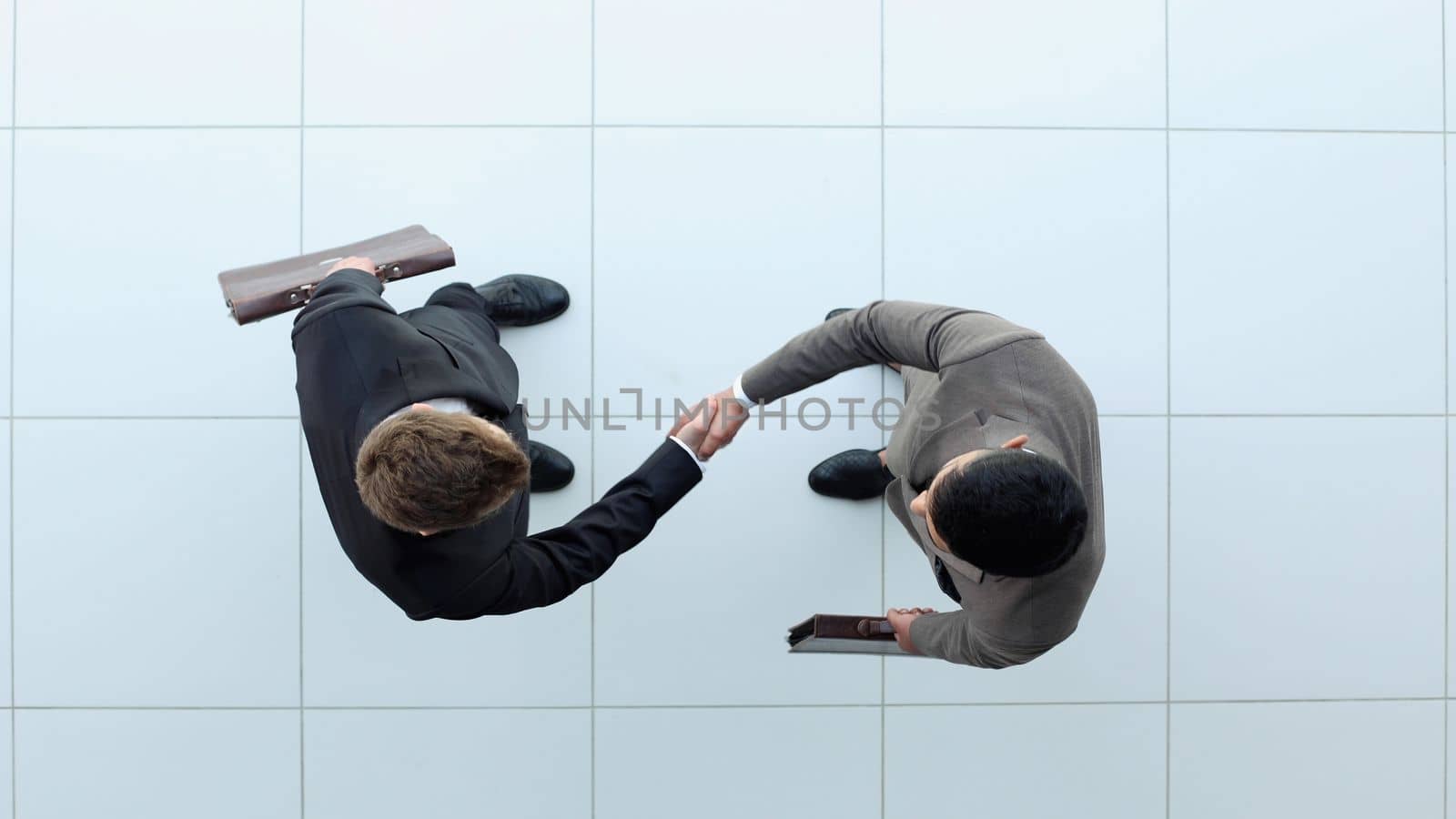 Two businessmen shake hands. view from above