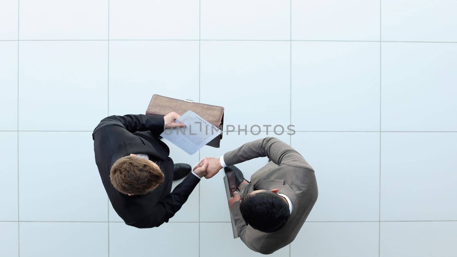 Two businessmen shake hands. view from above