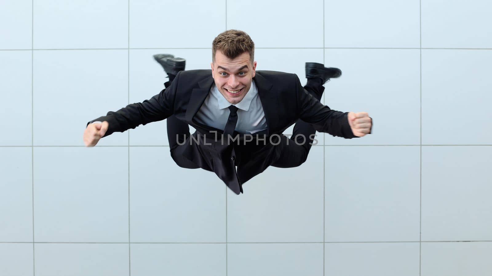 Celebrating success. Low angle view of excited young businessman keeping arms by Prosto