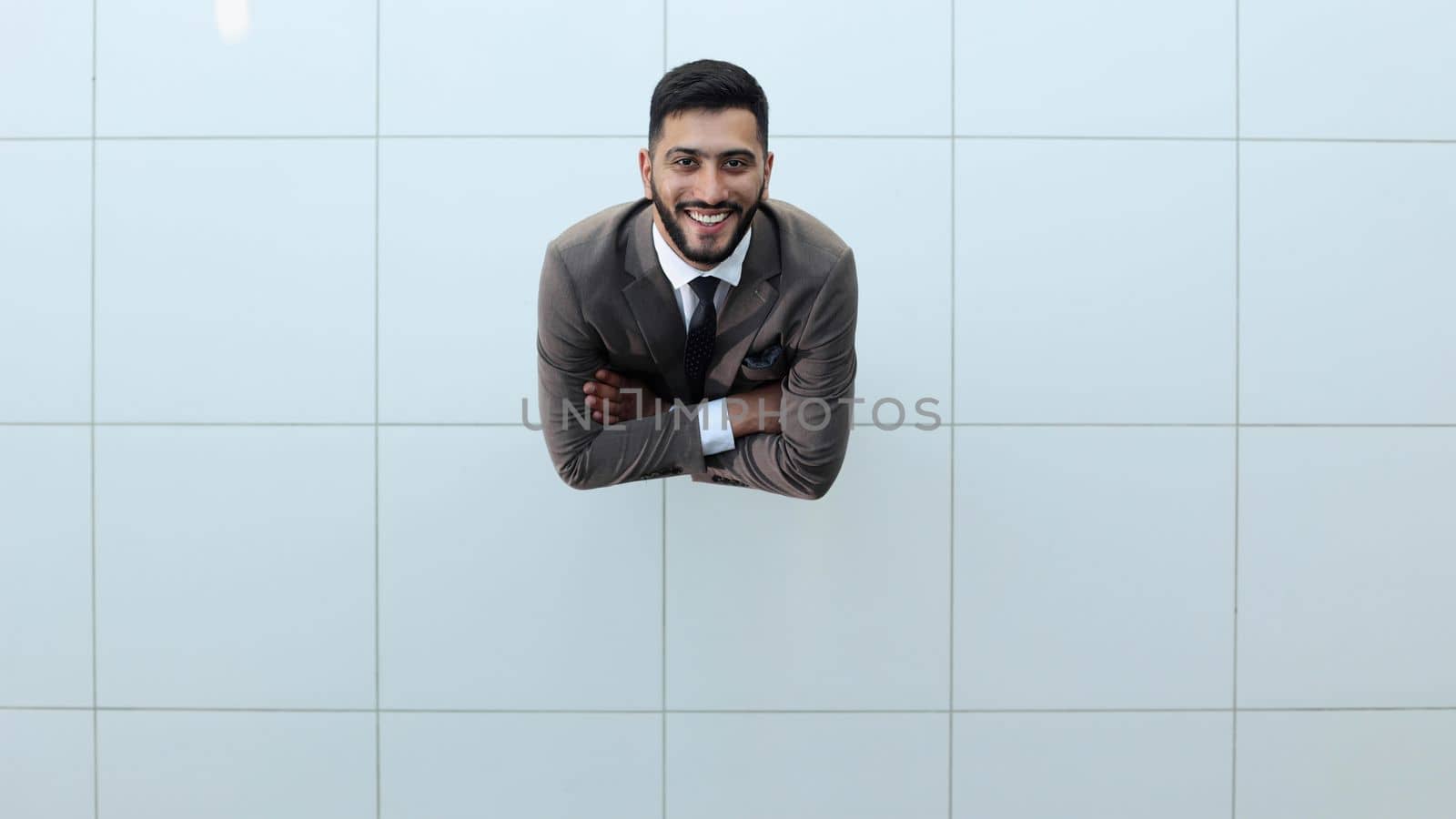 Handsome smiling business man in a suit standing with his arms crossed. by Prosto