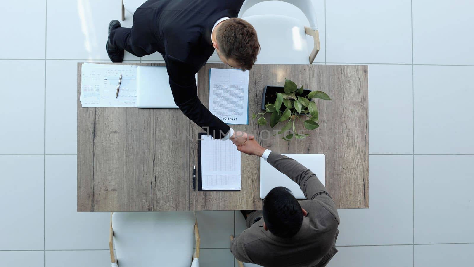 Two successful smiling businessmen are working on a laptop. view from above by Prosto