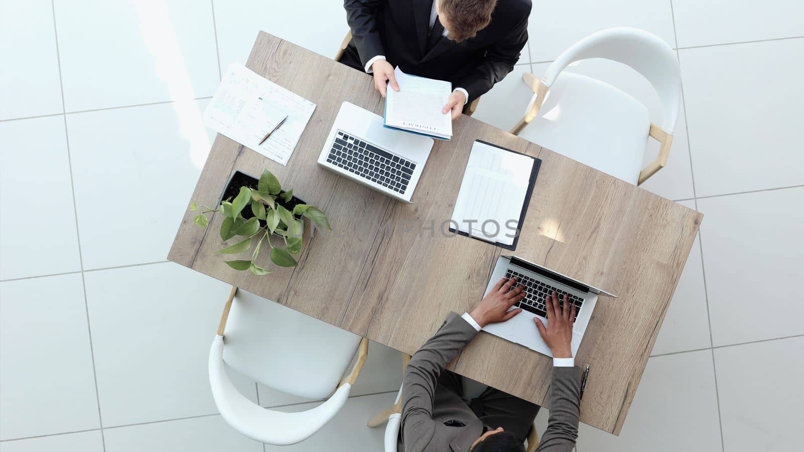 Two successful smiling businessmen are working on a laptop. view from above by Prosto