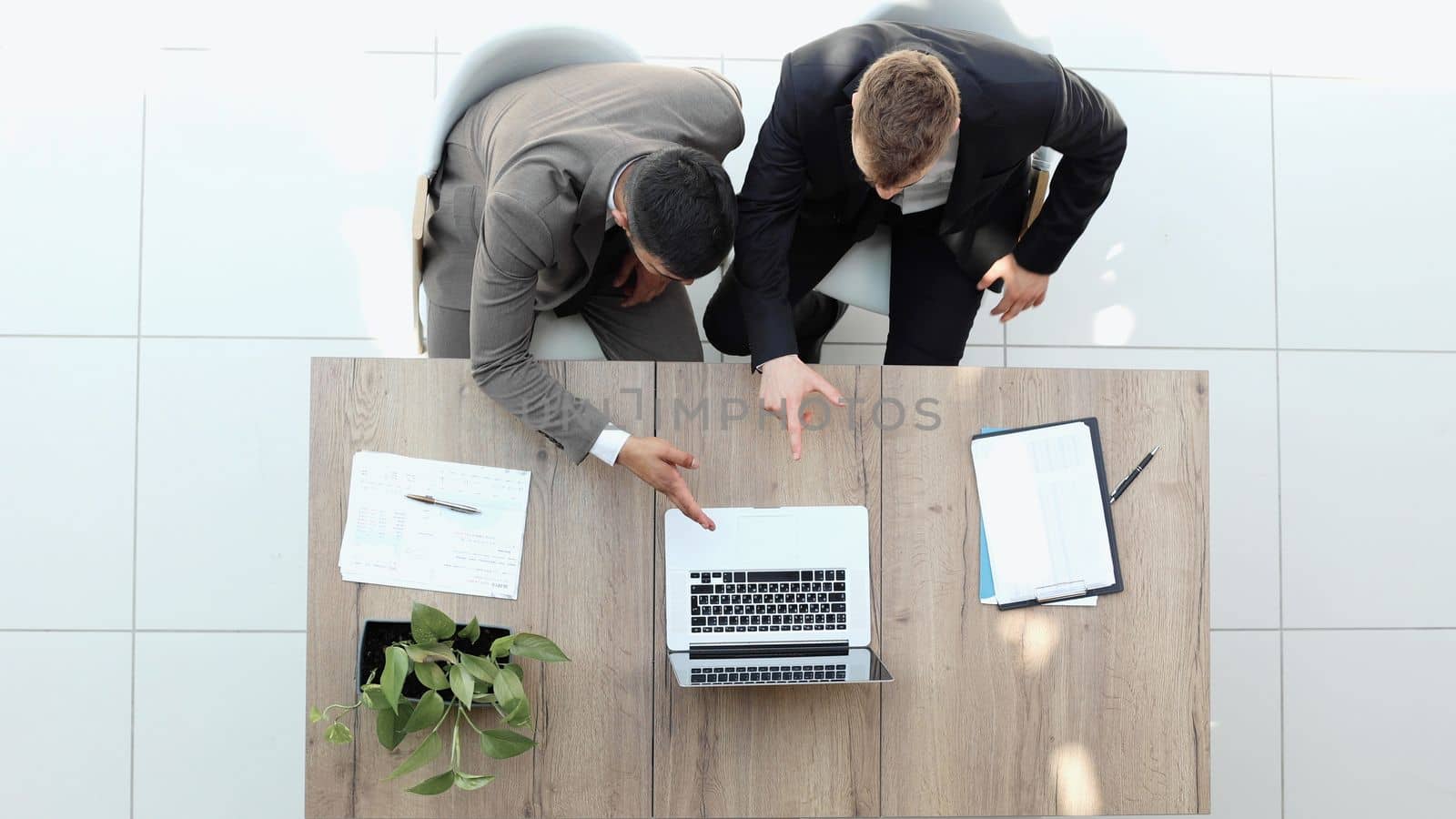 two businessmen sitting on a chair and watching something on a laptop