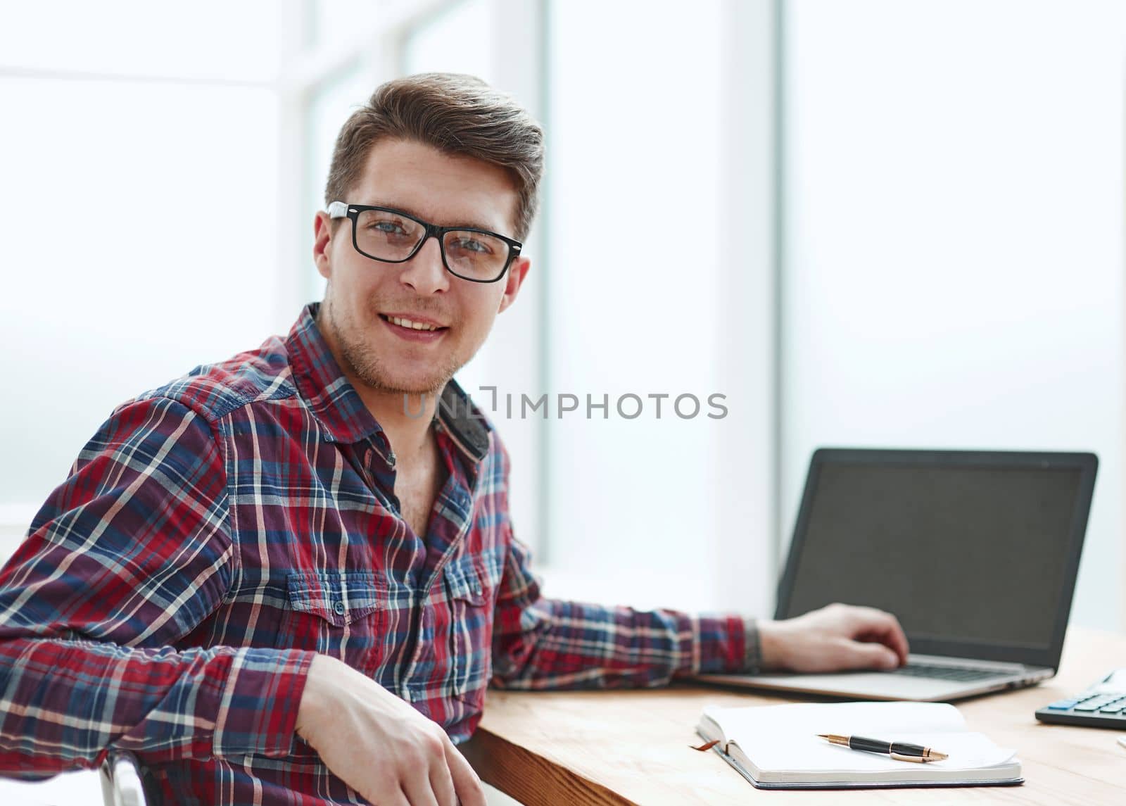 Young man with glasses working on his notebook, early in the morning, getting the business out of the way nice and early in the day