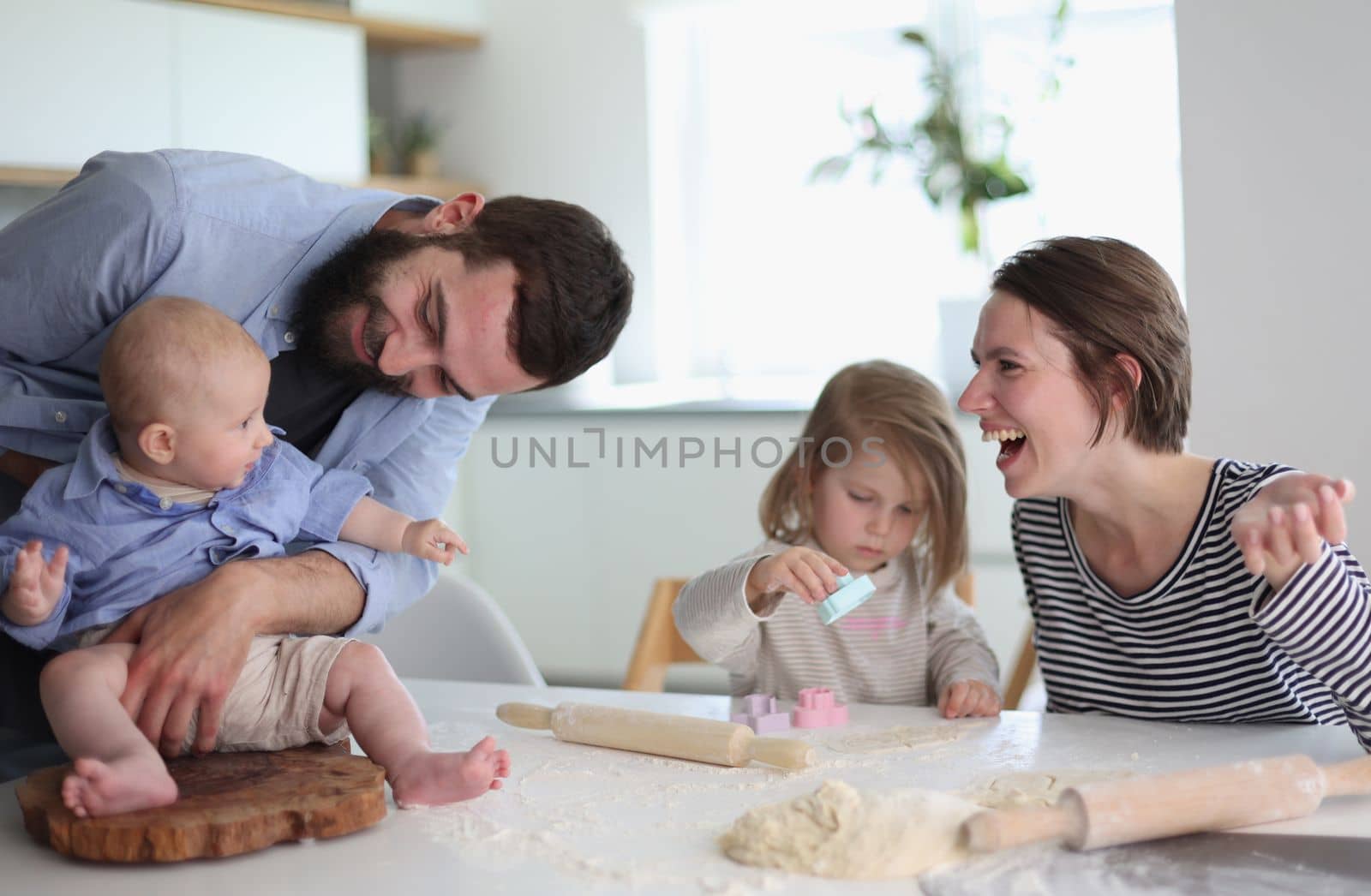 Happy parents playing with their children in the kitchen