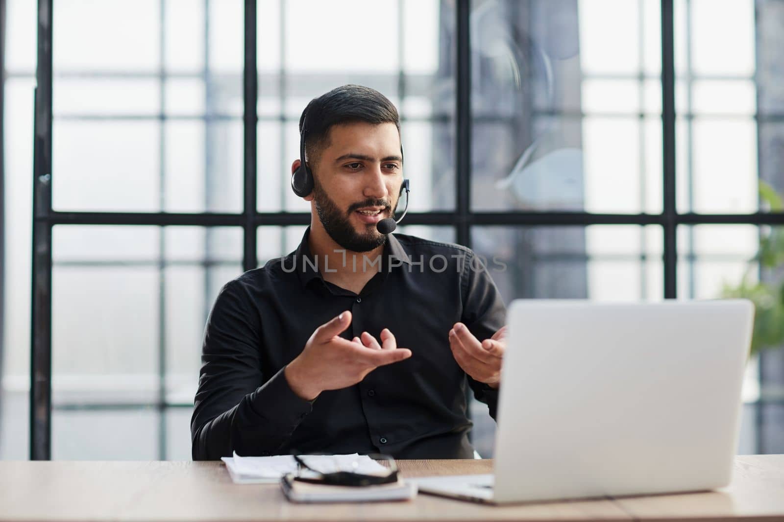 Positive businessman talking on headset at a computer