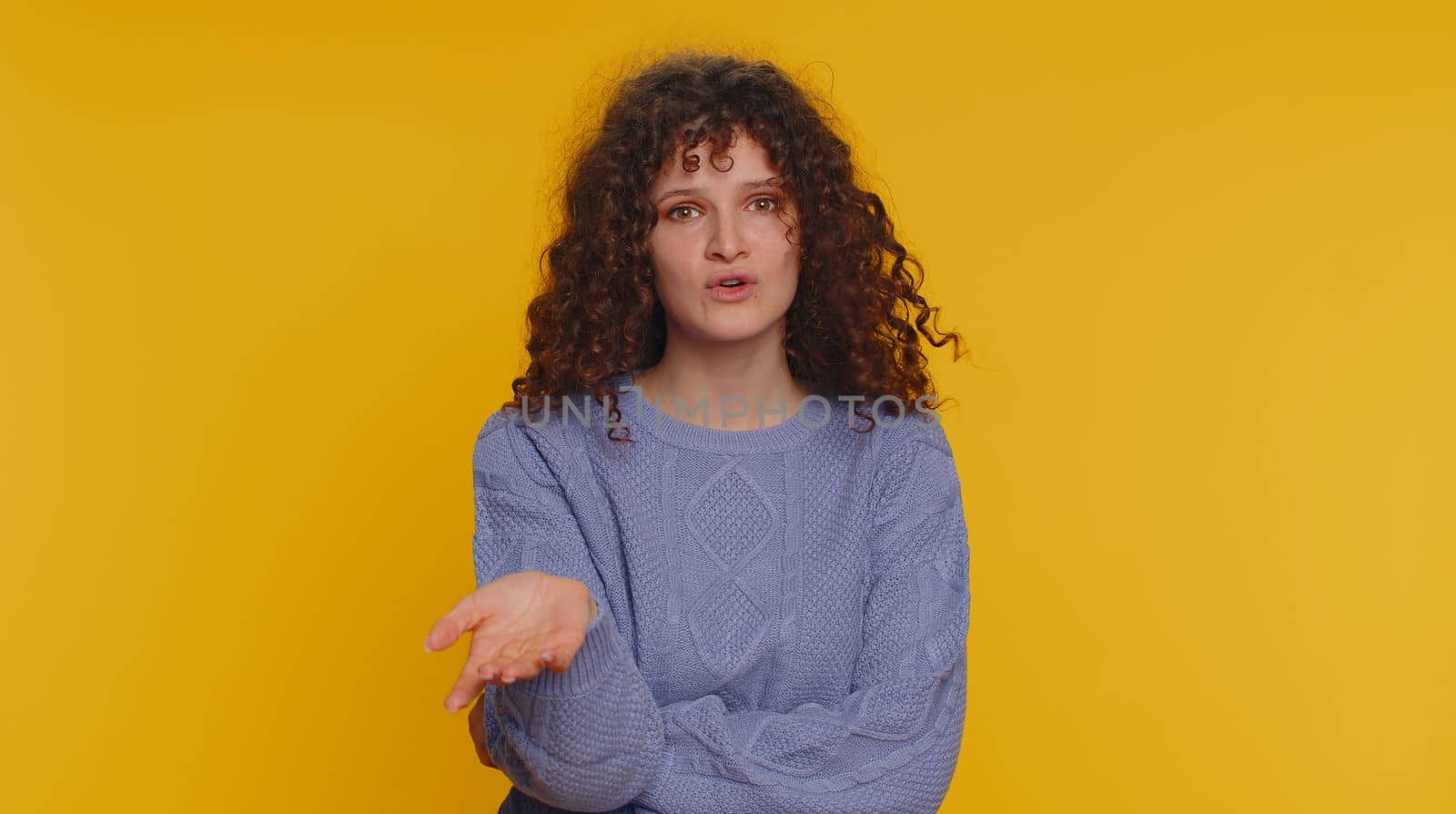 Quarrel. Displeased curly haired woman gesturing hands with irritation and displeasure, blaming scolding for failure, asking why this happened. Young teen girl isolated on yellow studio background