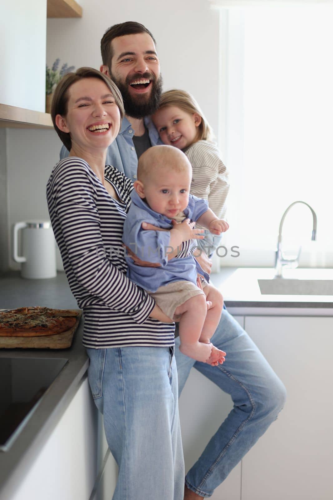 Family of 4 posing in the kitchen smiling and happy