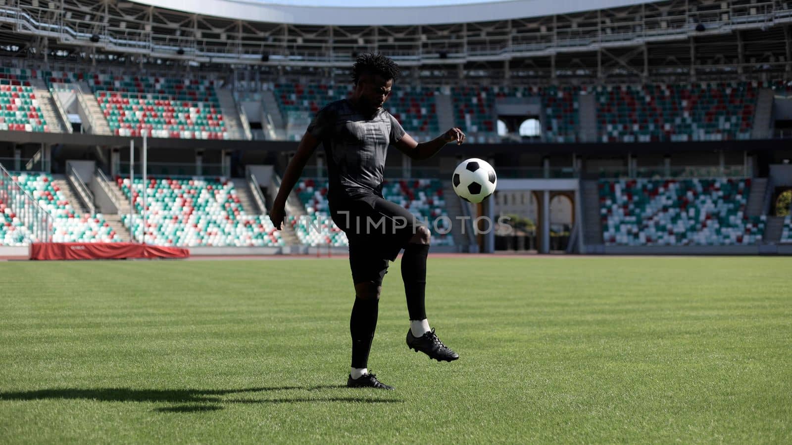 African American man playing football on the stadium field.