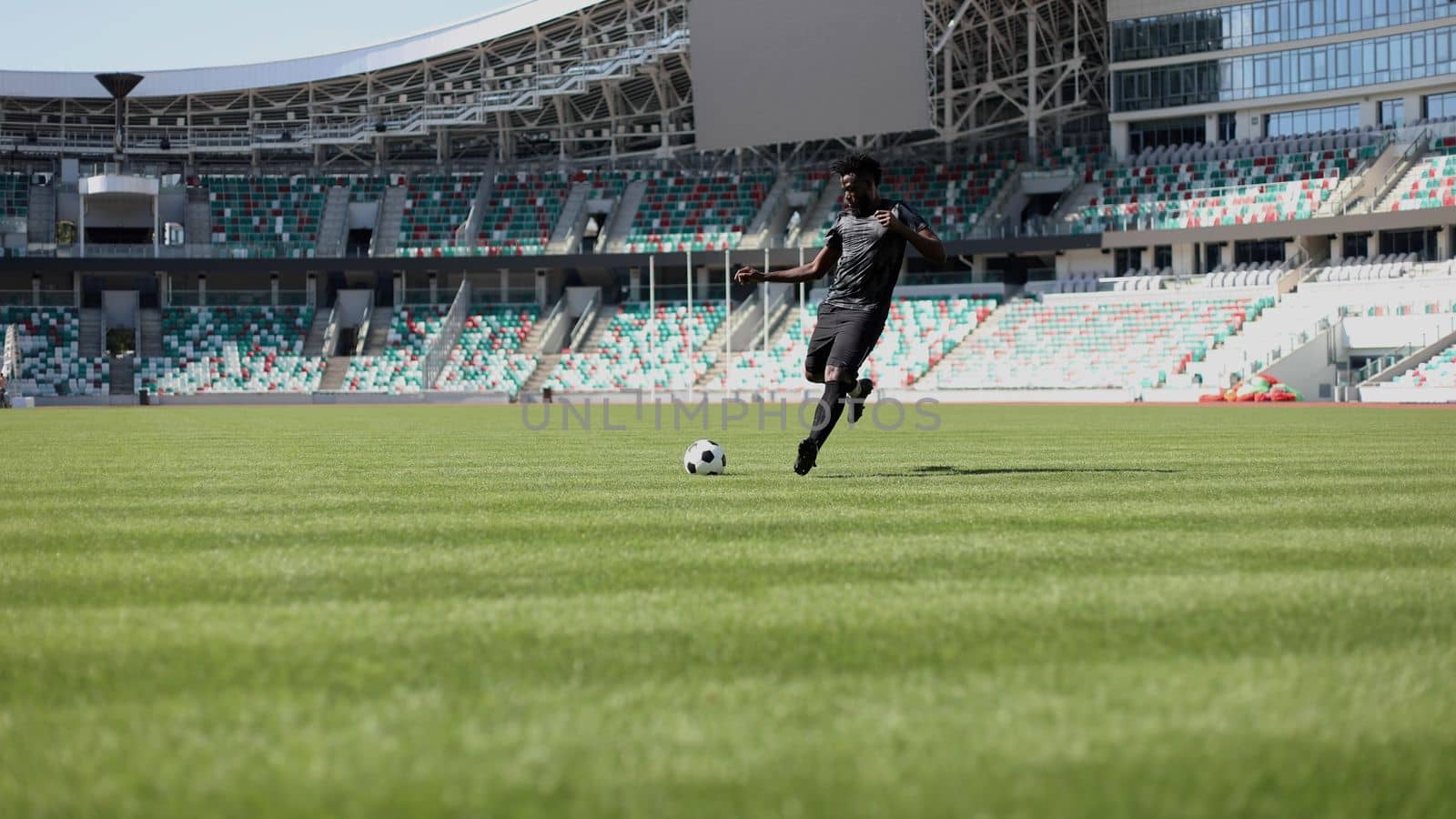 African American man playing football on the stadium field.