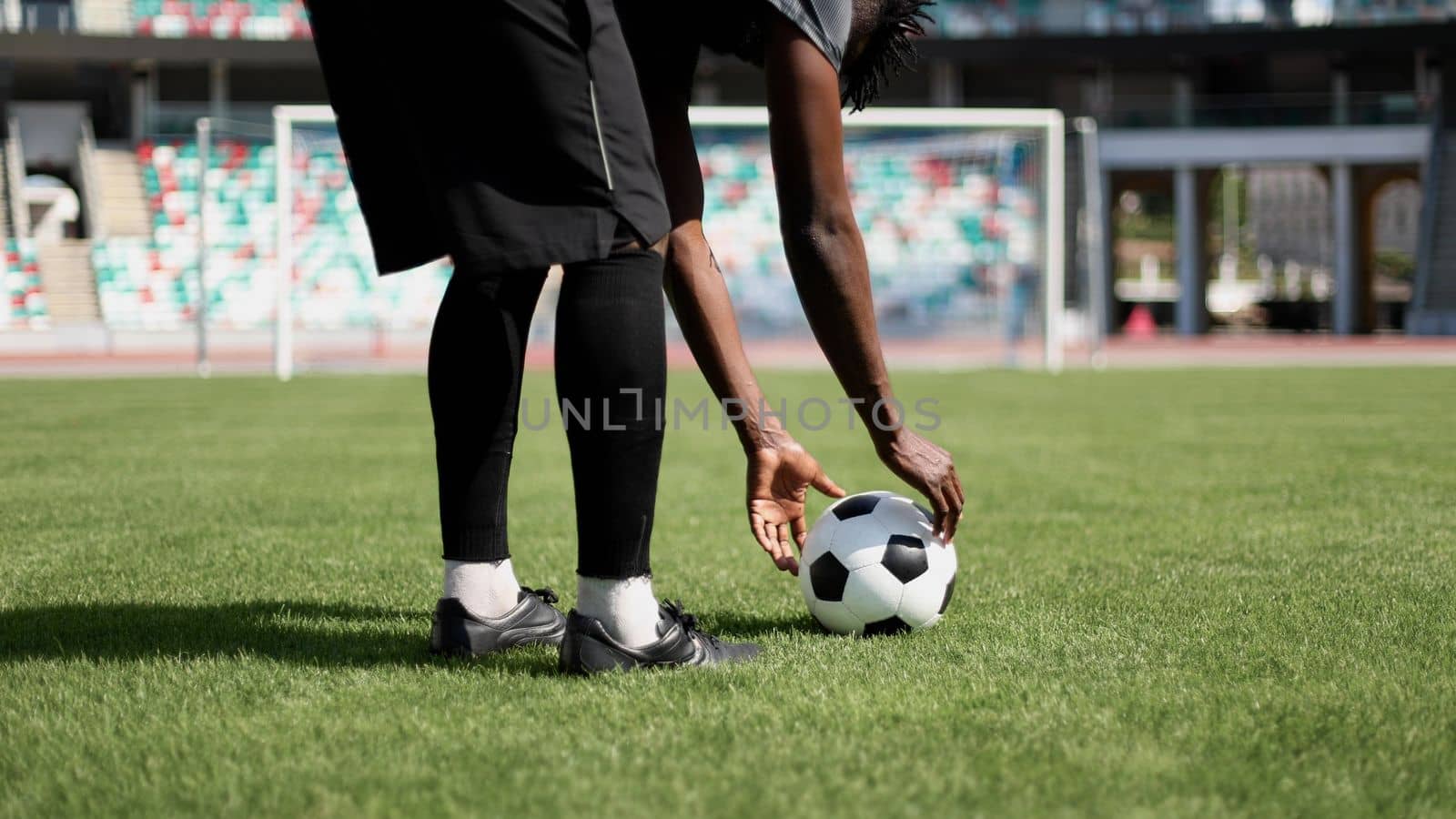 African American man playing football on the stadium field.