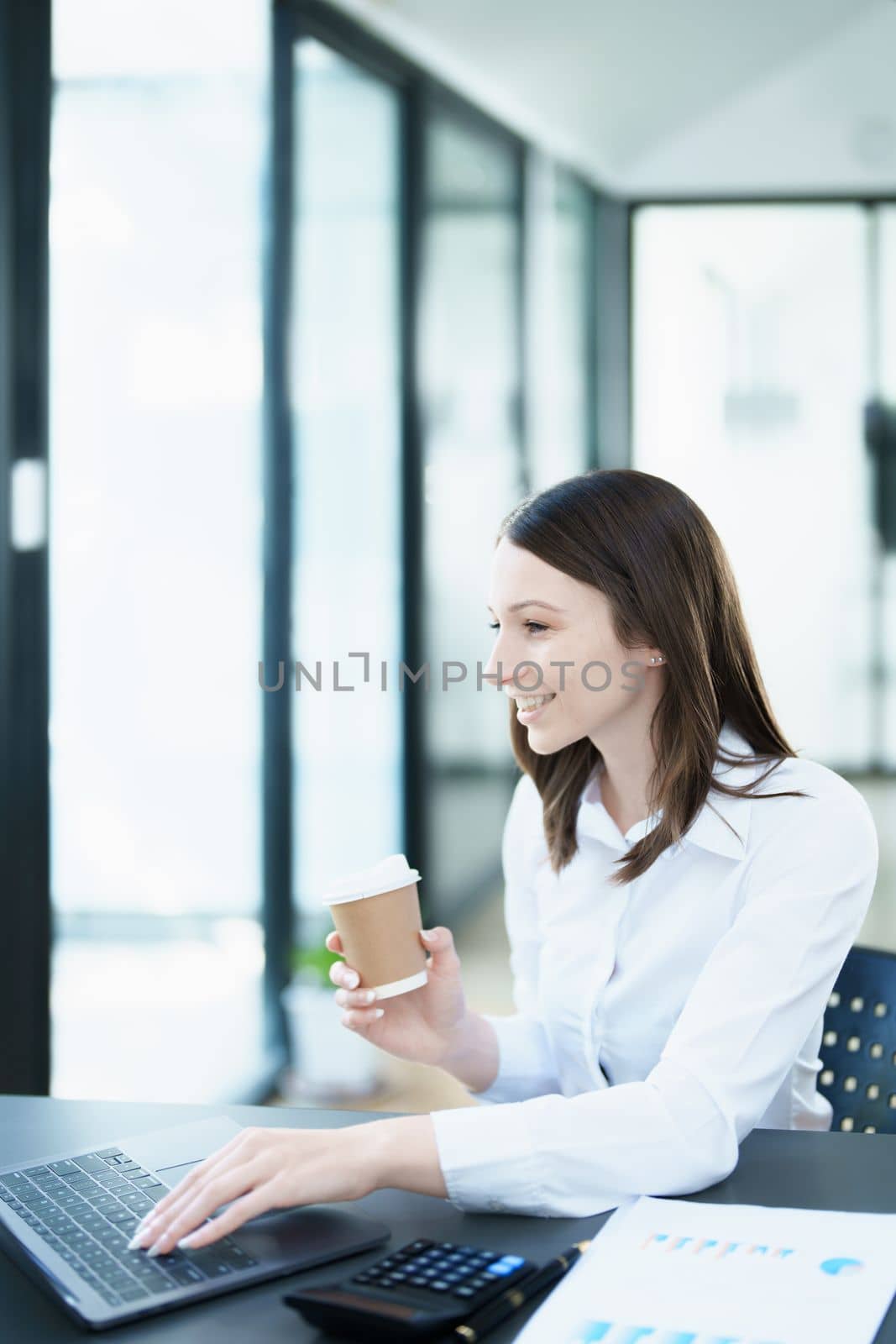 Portrait of a business woman using laptop computer and drinking coffee