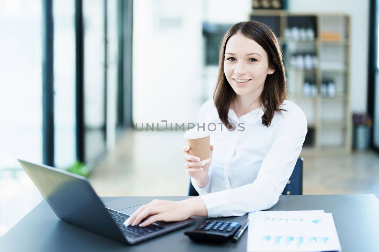 Portrait of a business woman using laptop computer and drinking coffee