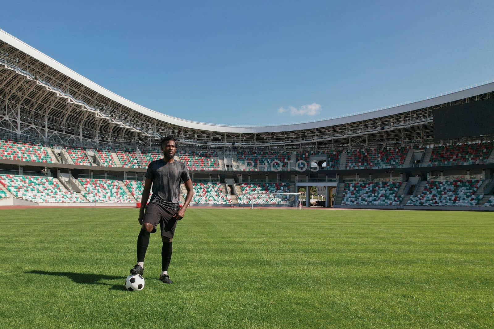 Man holding soccer ball with his foot in the stadium