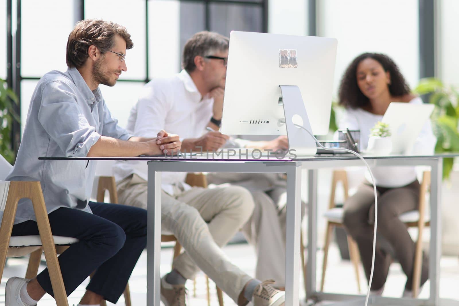 discussion of business people in the office sitting at the table looking at the monitor