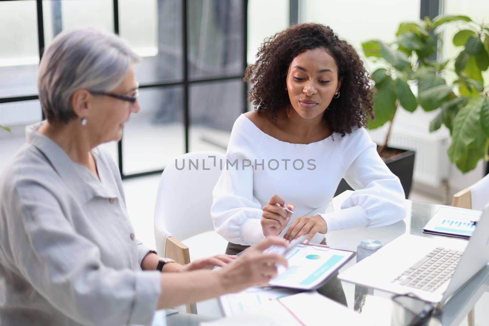 Business women smile while working together on a laptop at a table in the boardroom in the office