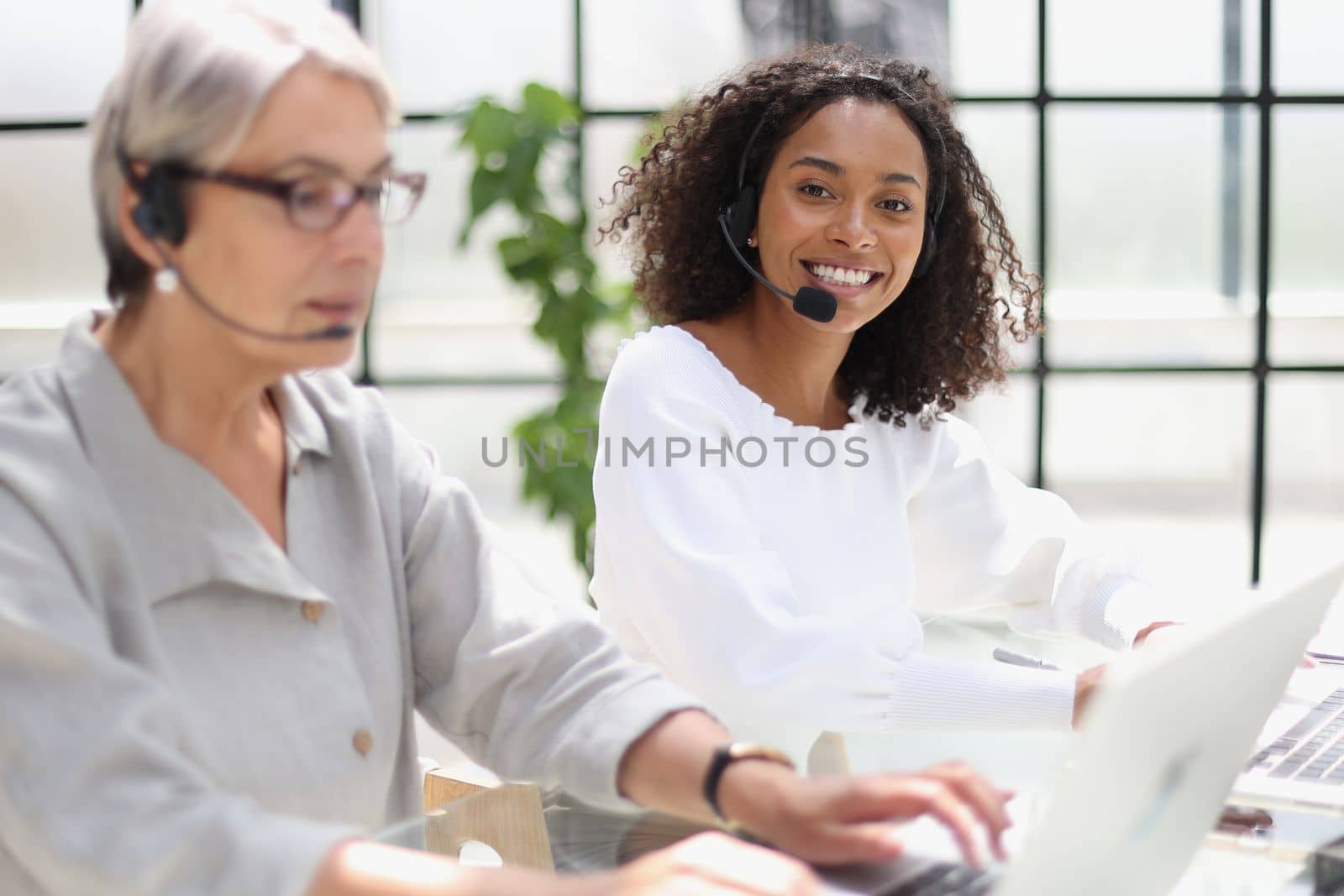 Young friendly operator woman agent with headsets working in a call centre