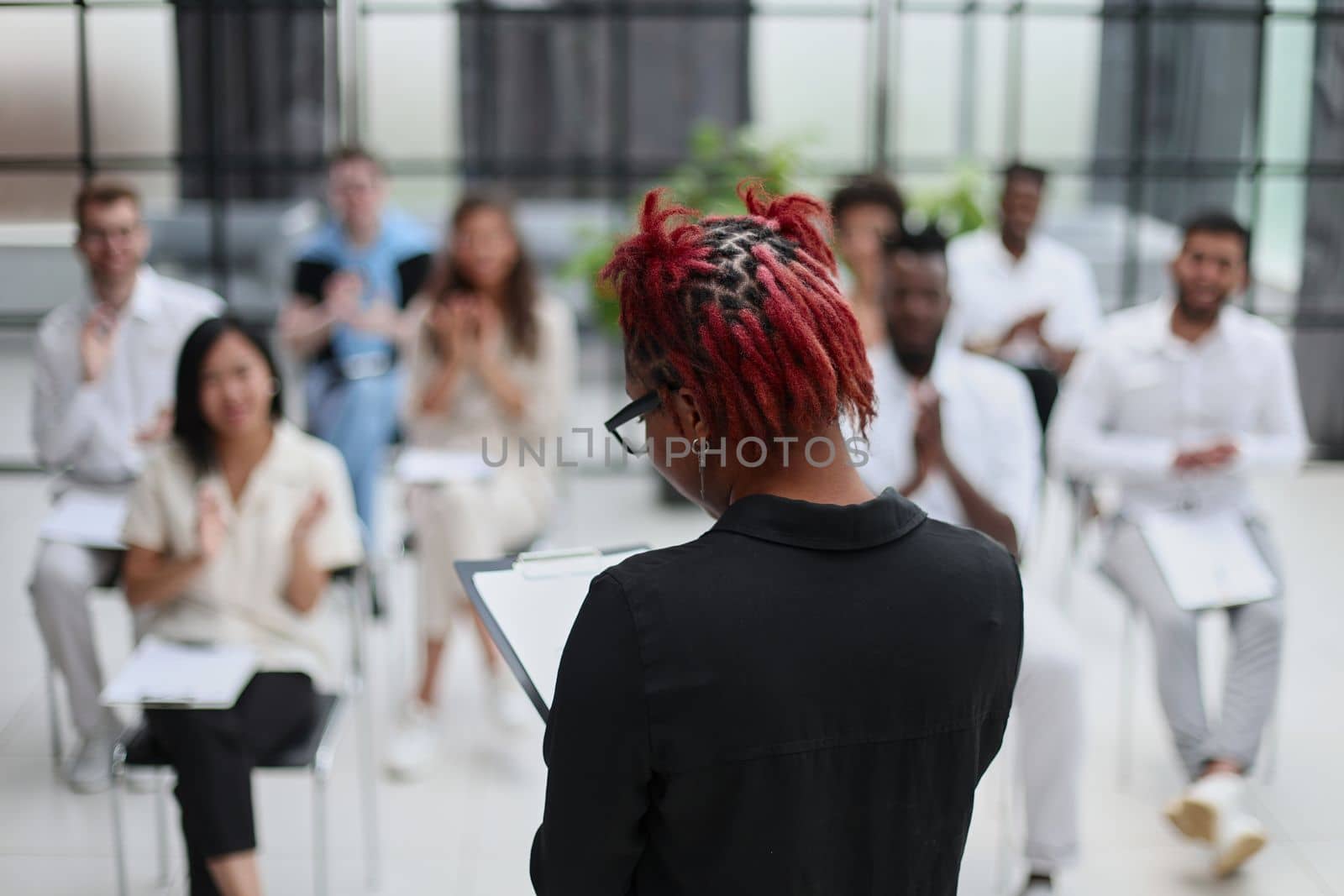 african american woman with a notepad against the background of other people at the seminar. business concept