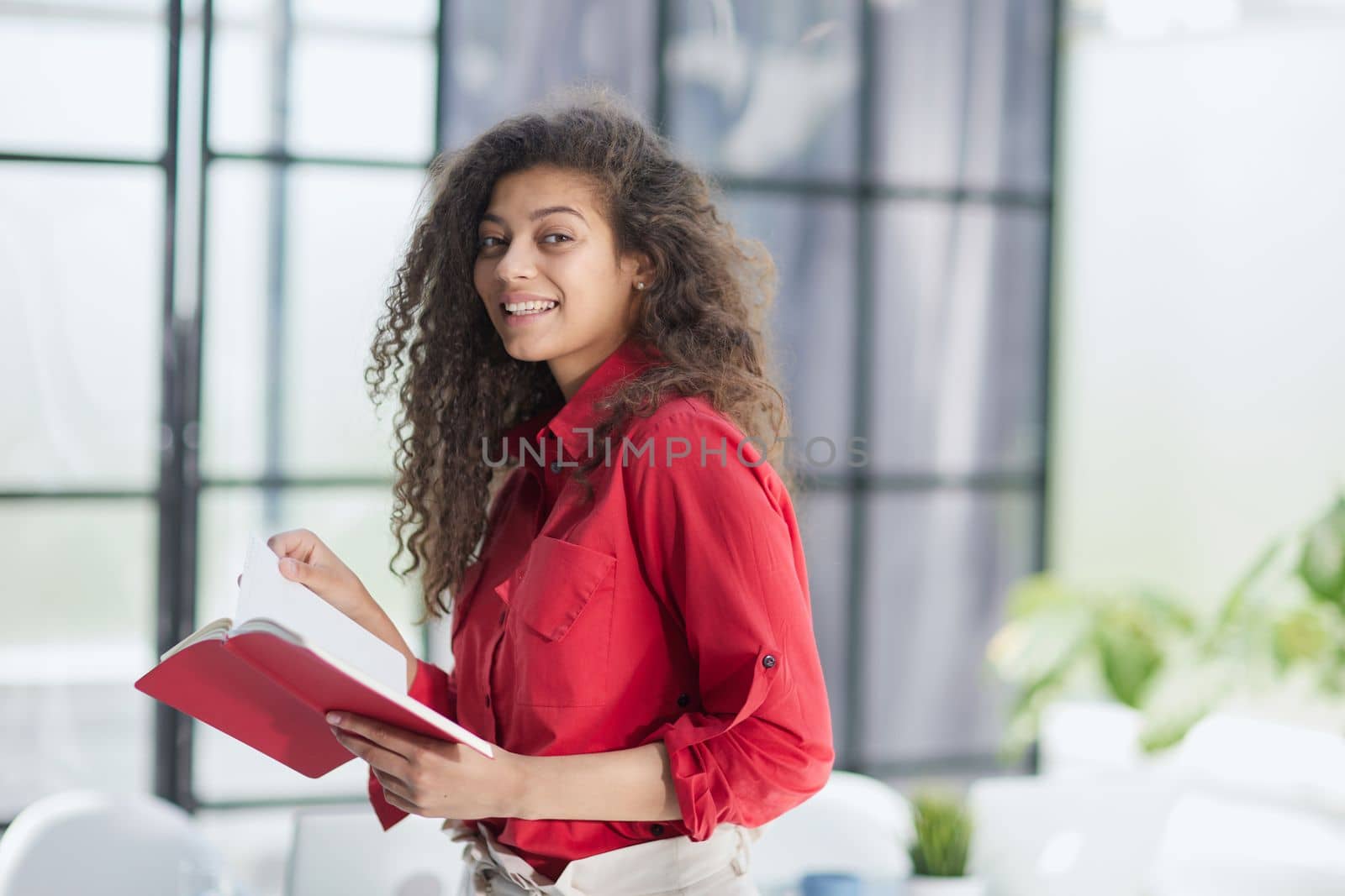 Young dedicated woman revising papers while working on project at laptop in loft office