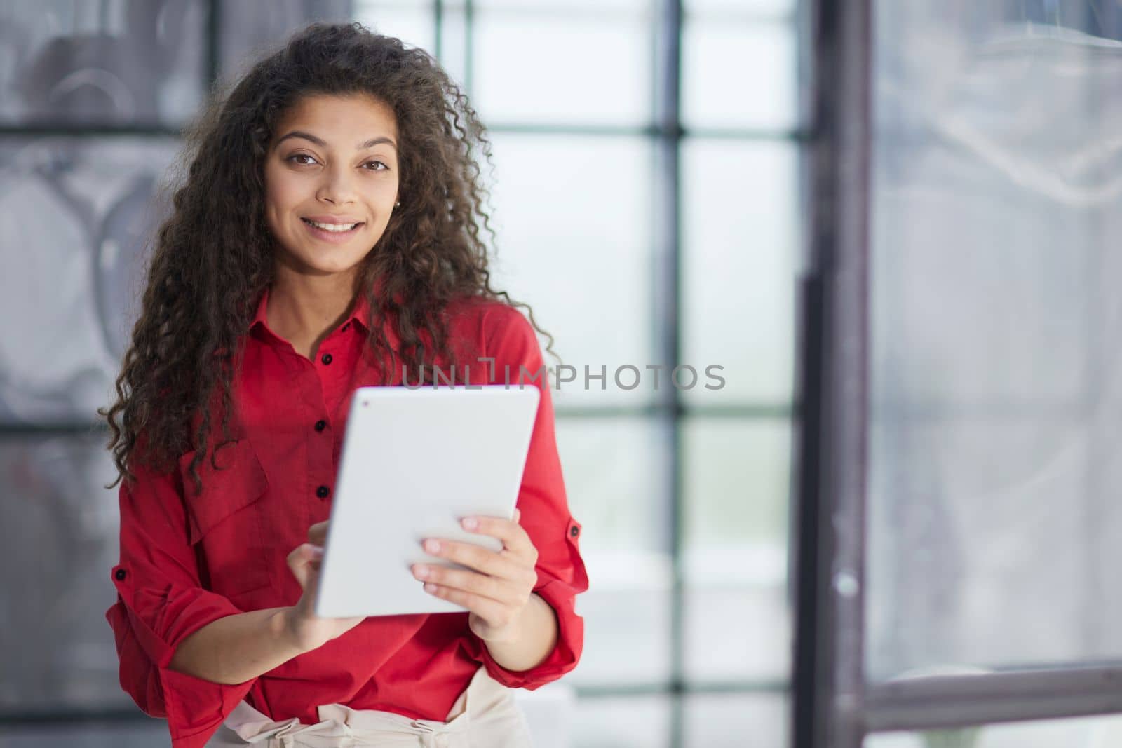 Elegant businesswoman standing in office with digital tablet