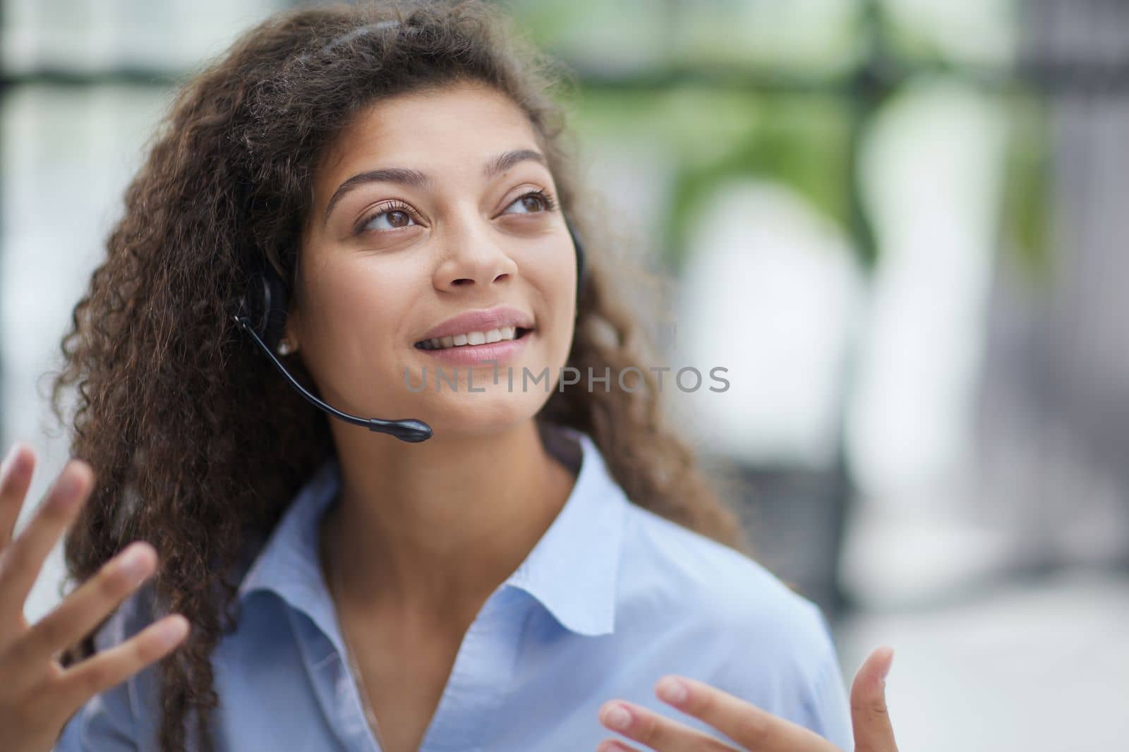 Beautiful smiling woman consultant in headphones with a microphone. Remote work from home.