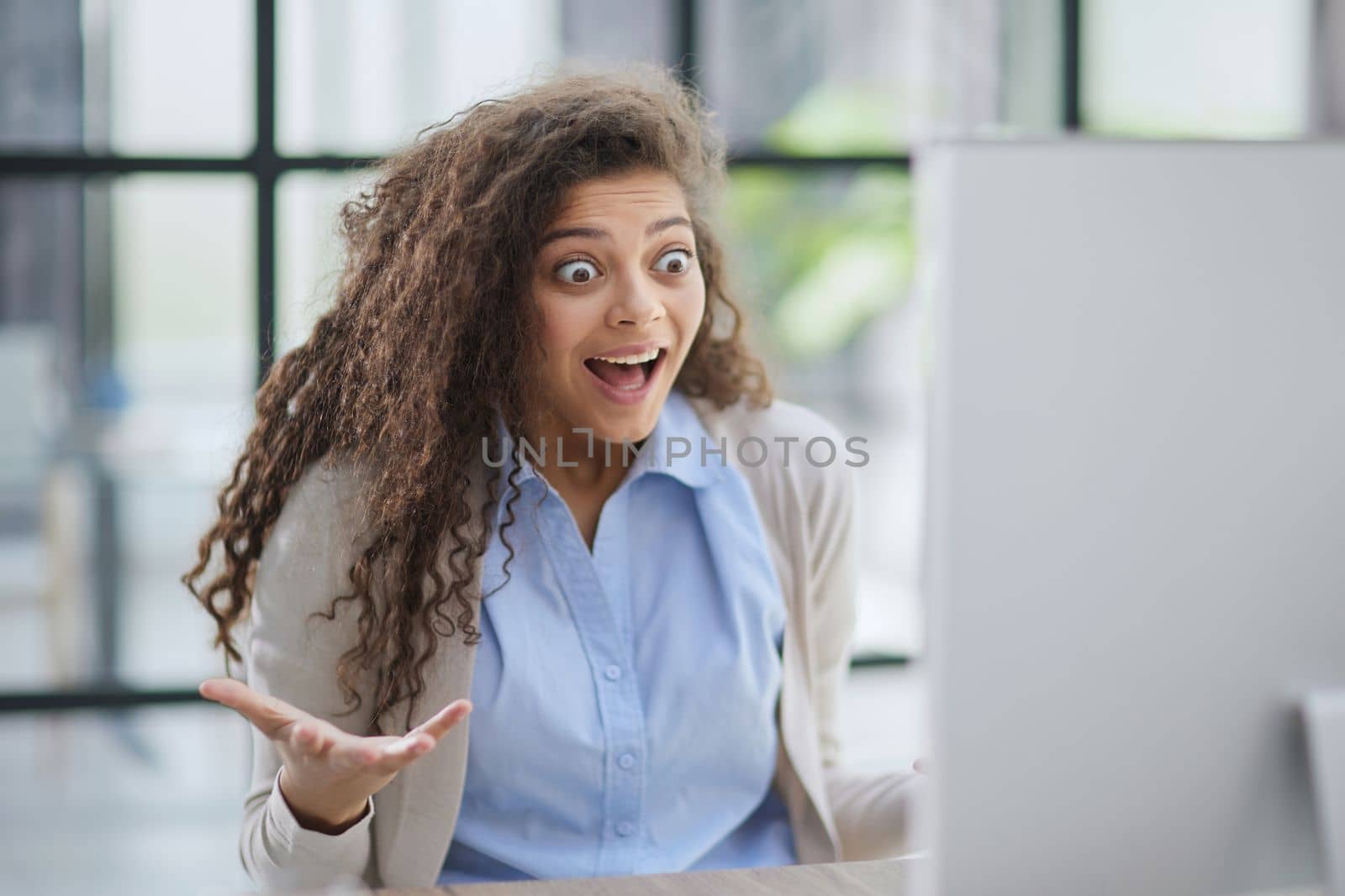 expressive young woman open mouth checking discounts for online shopping sitting at desktop .