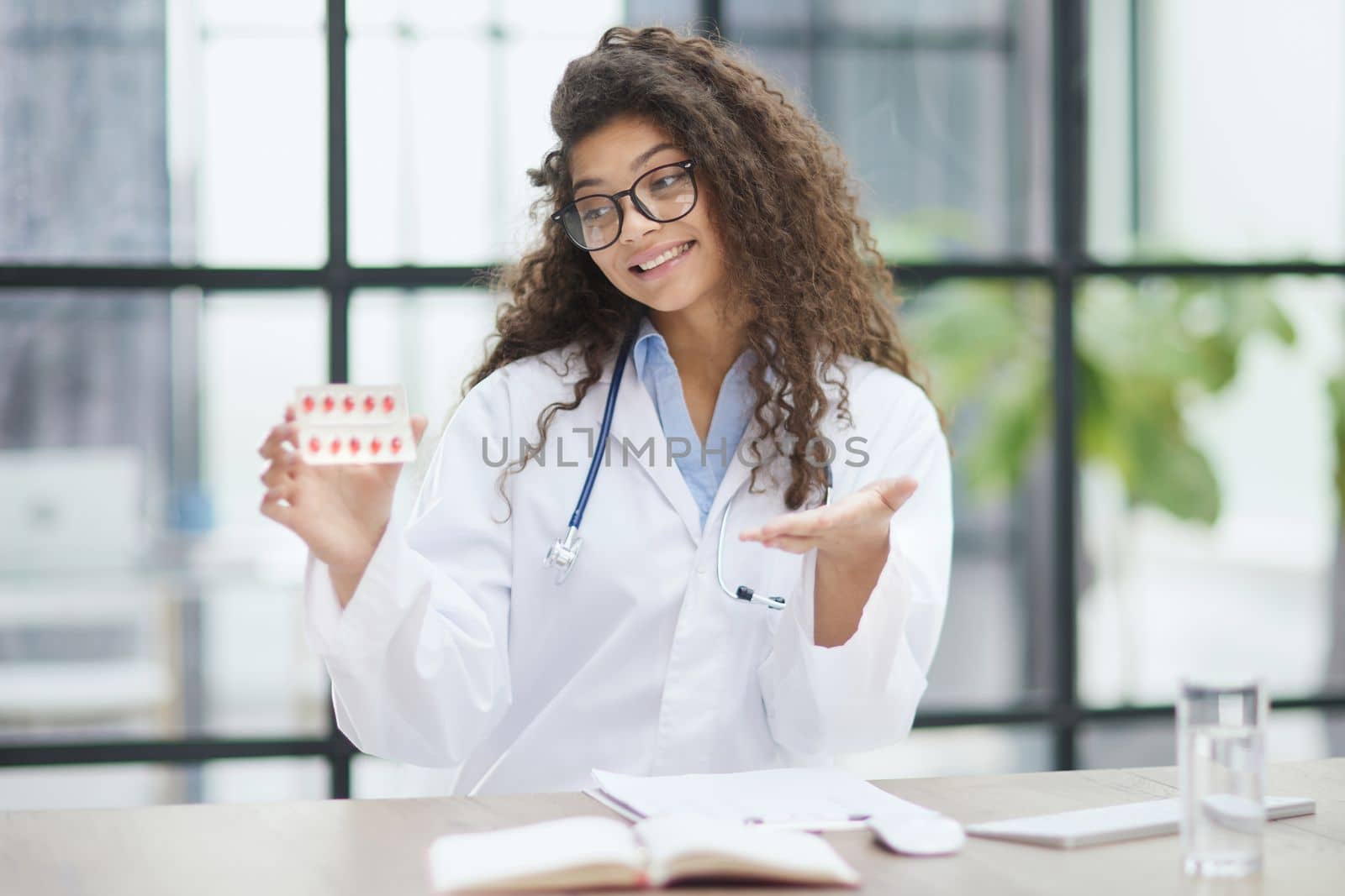 Portrait of young female doctor in white coat at workplace