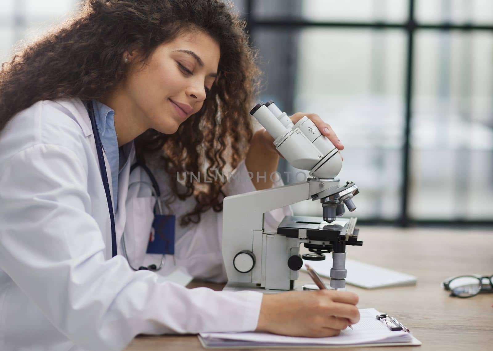 Attractive female scientist looking through a microscope