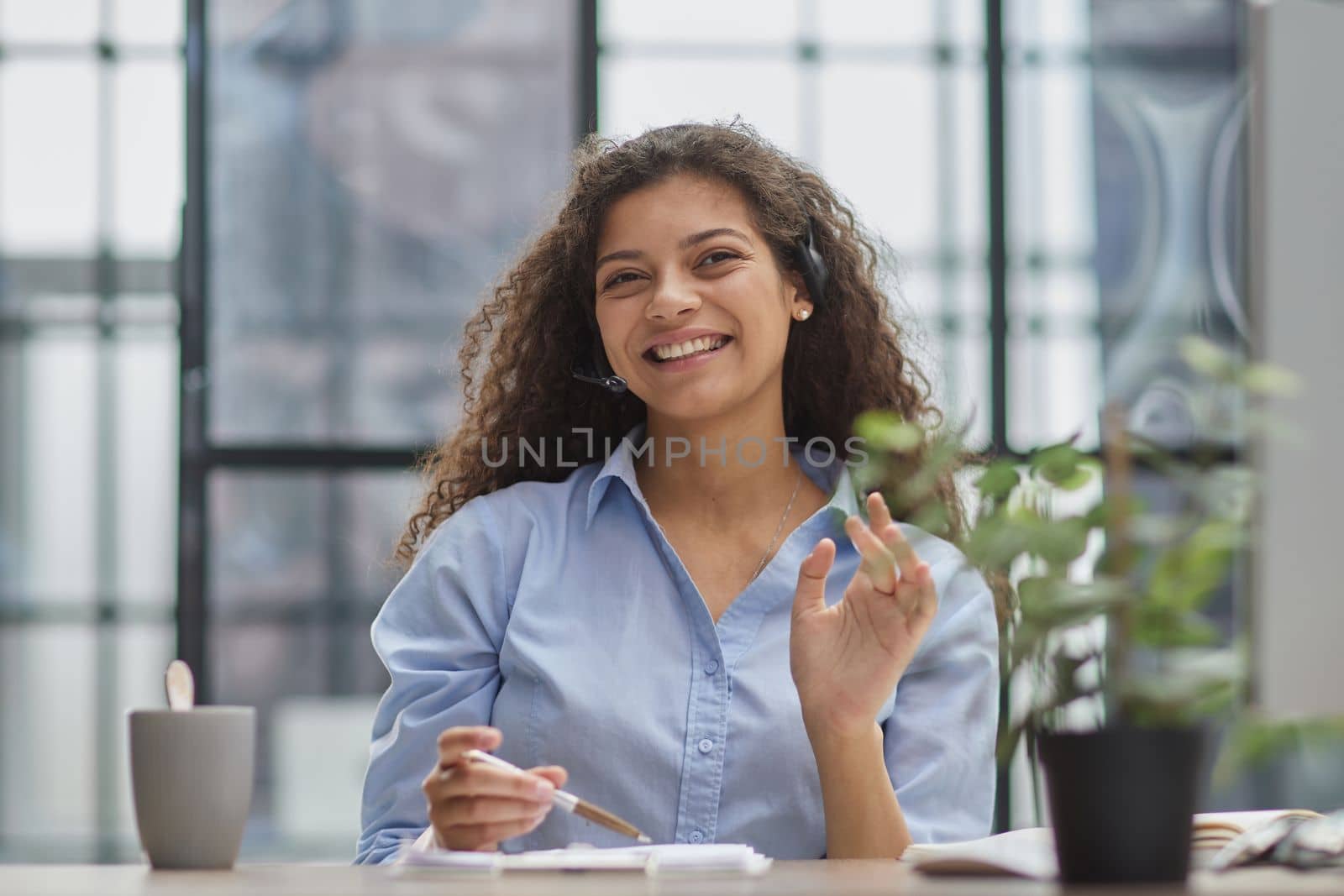 Smiling businesswoman or helpline operator with headset and computer at office