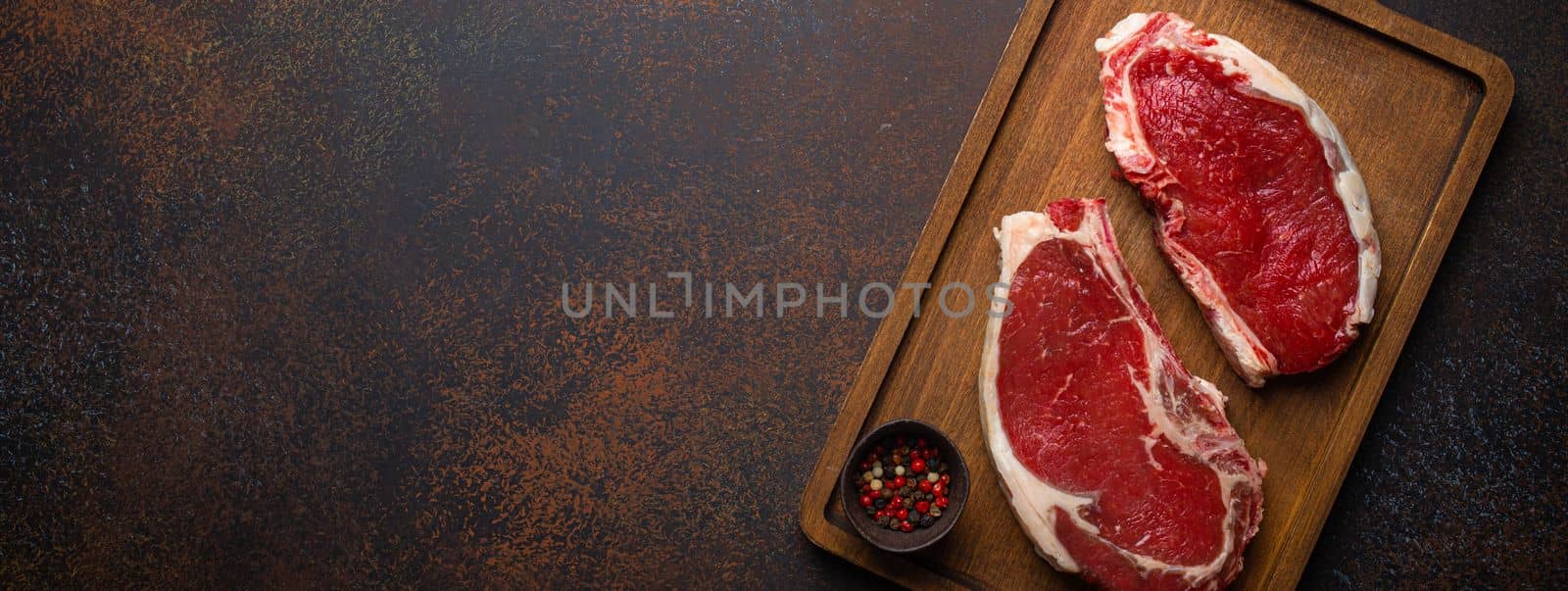 Two raw meat beef rib eye marbled steaks on wooden cutting board by its_al_dente
